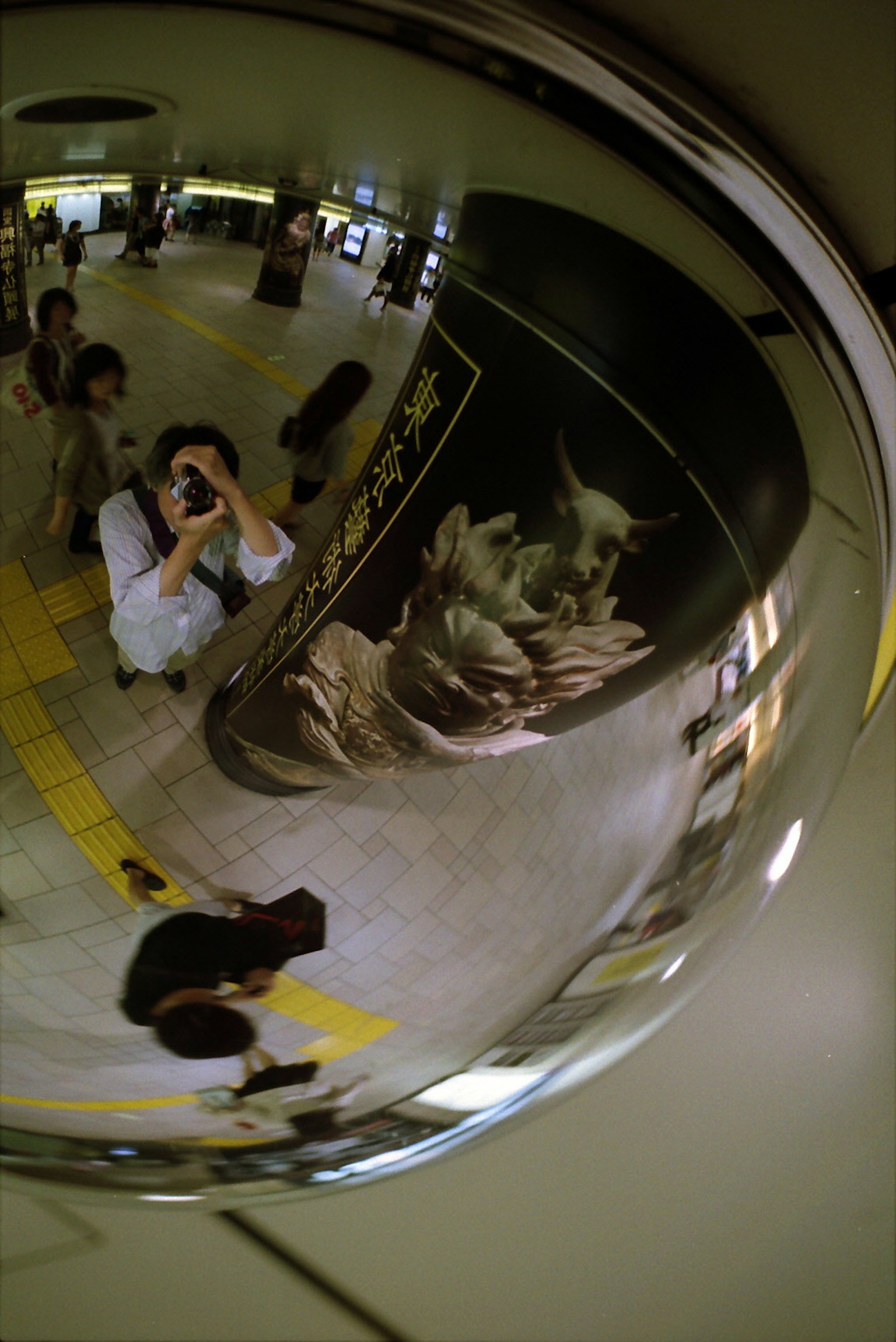 Reflection of people and artwork in a station mirror