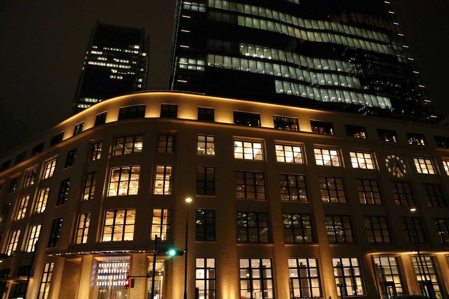 Historic building with illuminated windows and modern skyscraper at night