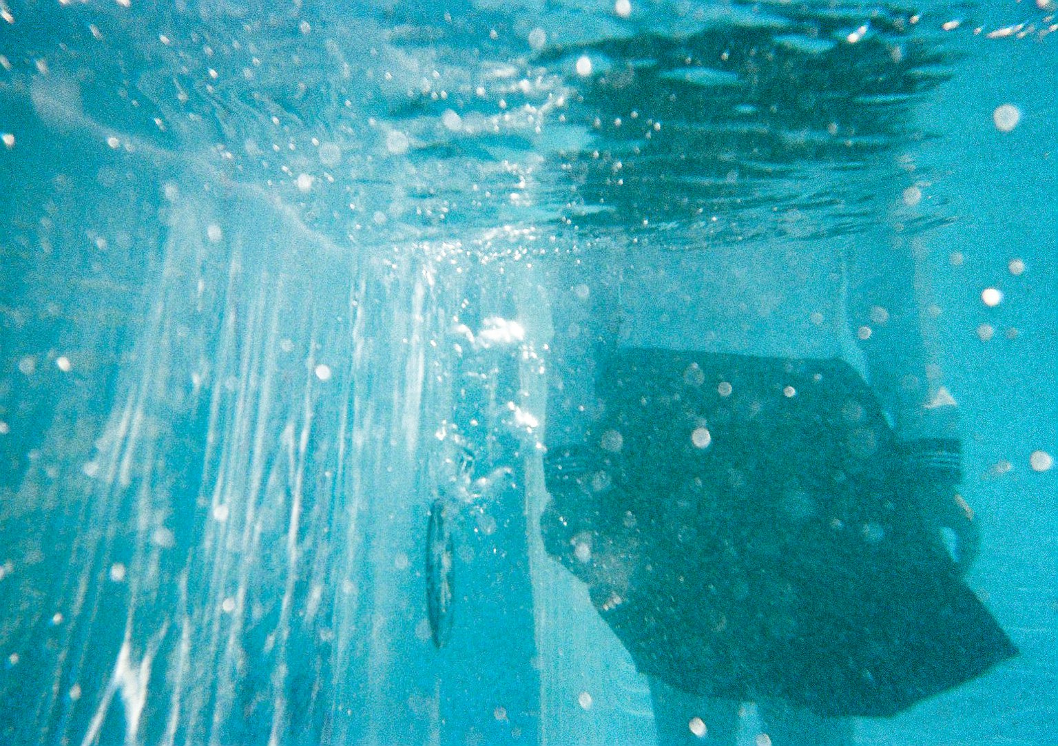 Silueta de una persona bajo el agua con un fondo azul y burbujas