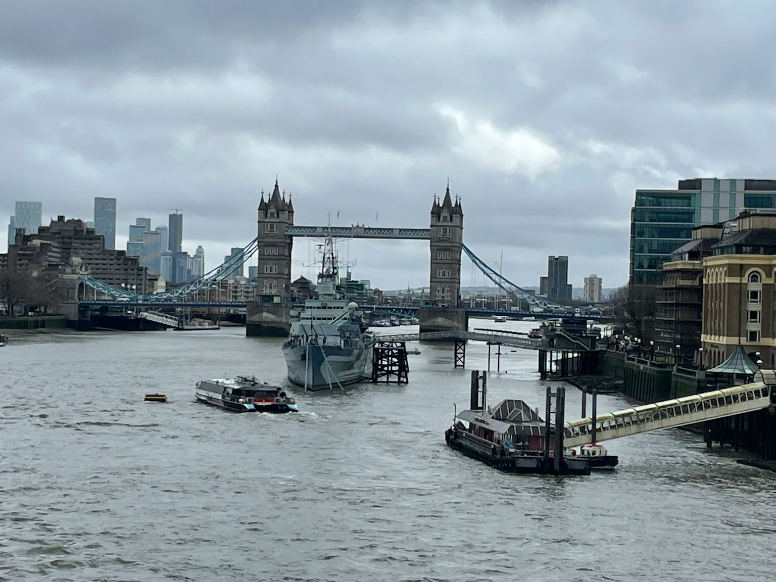 Blick auf die Tower Bridge und die Themse in London mit bewölktem Himmel und modernen Gebäuden