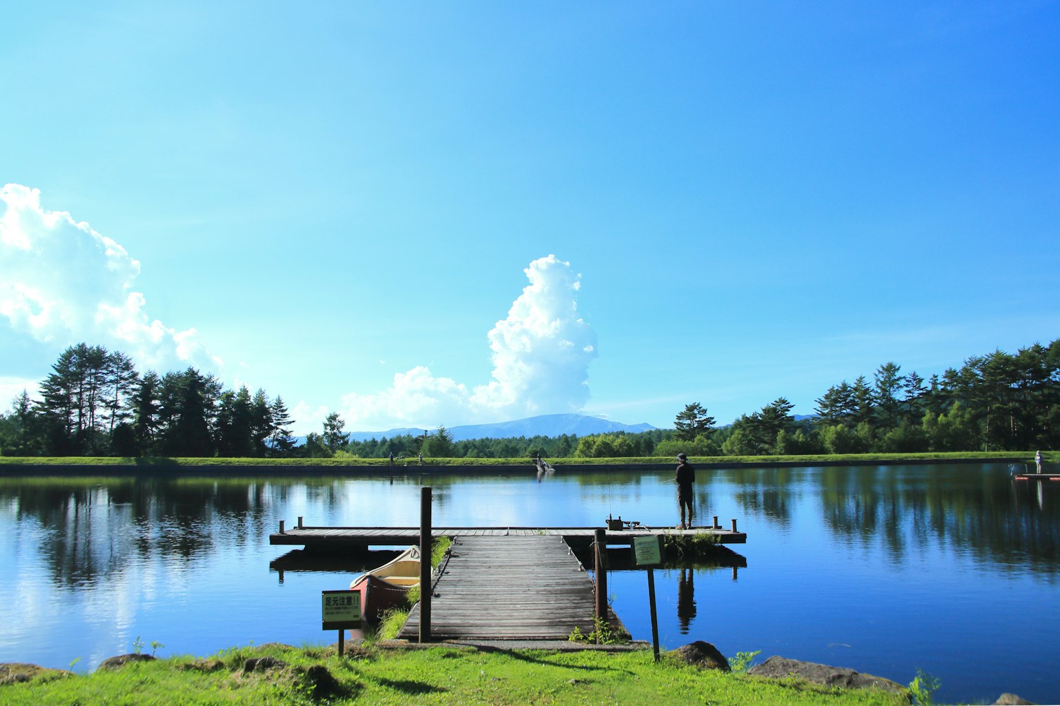 ทะเลสาบเงียบสงบใต้ท้องฟ้าสีฟ้าพร้อมท่าเทียบเรือไม้
