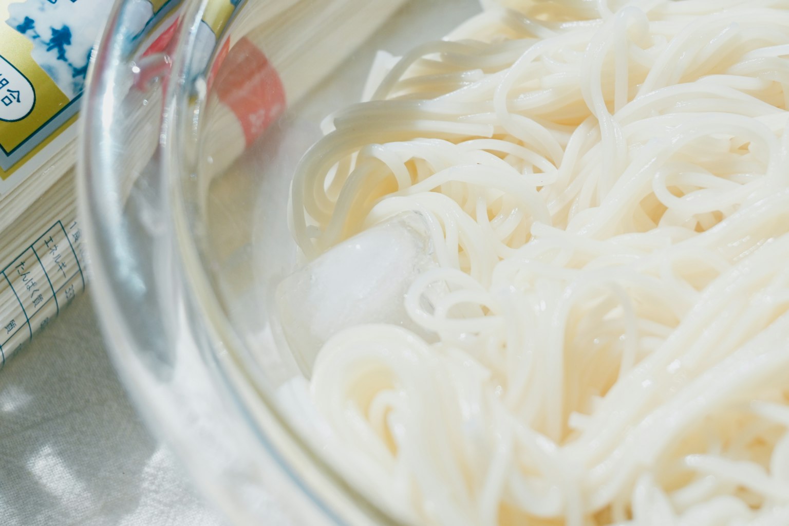 Noodles freddi in una ciotola di vetro trasparente con bacchette