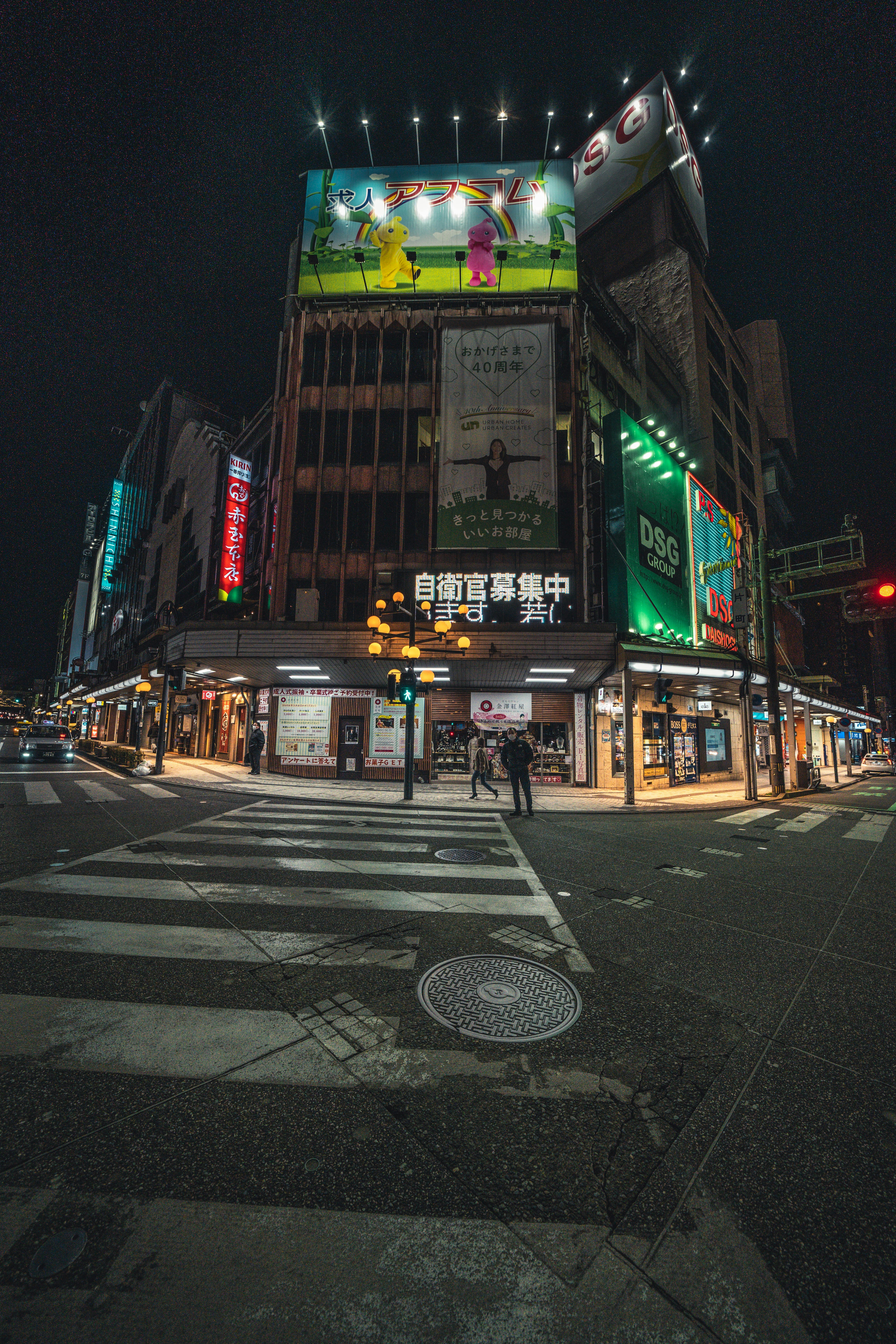 夜の交差点に面したビル群とネオン看板の街並み