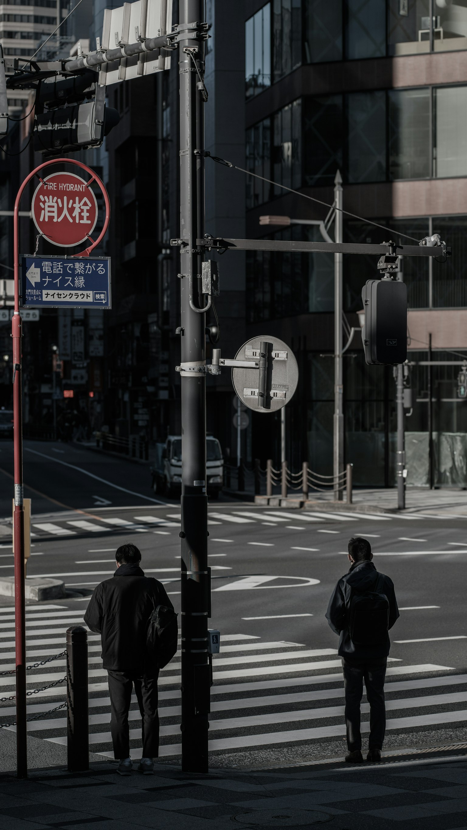 Due uomini in attesa a un semaforo in un attraversamento pedonale urbano