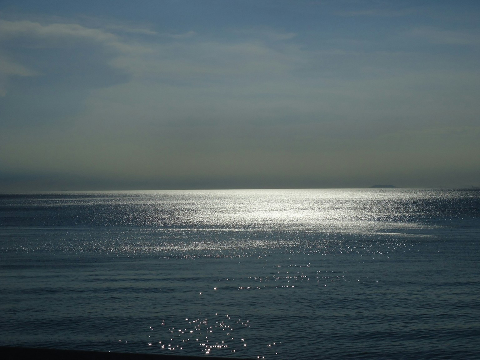 Calm sea reflecting light with a blue sky