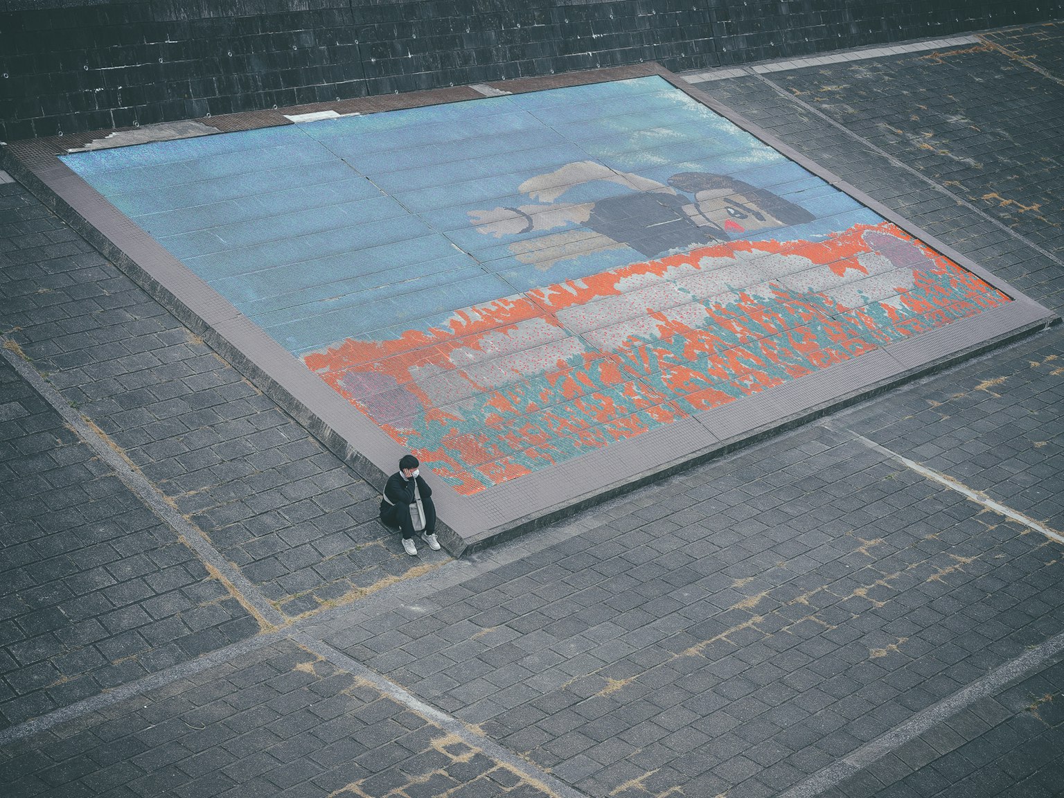 Large artwork with blue background and orange painting featuring a person sitting in front