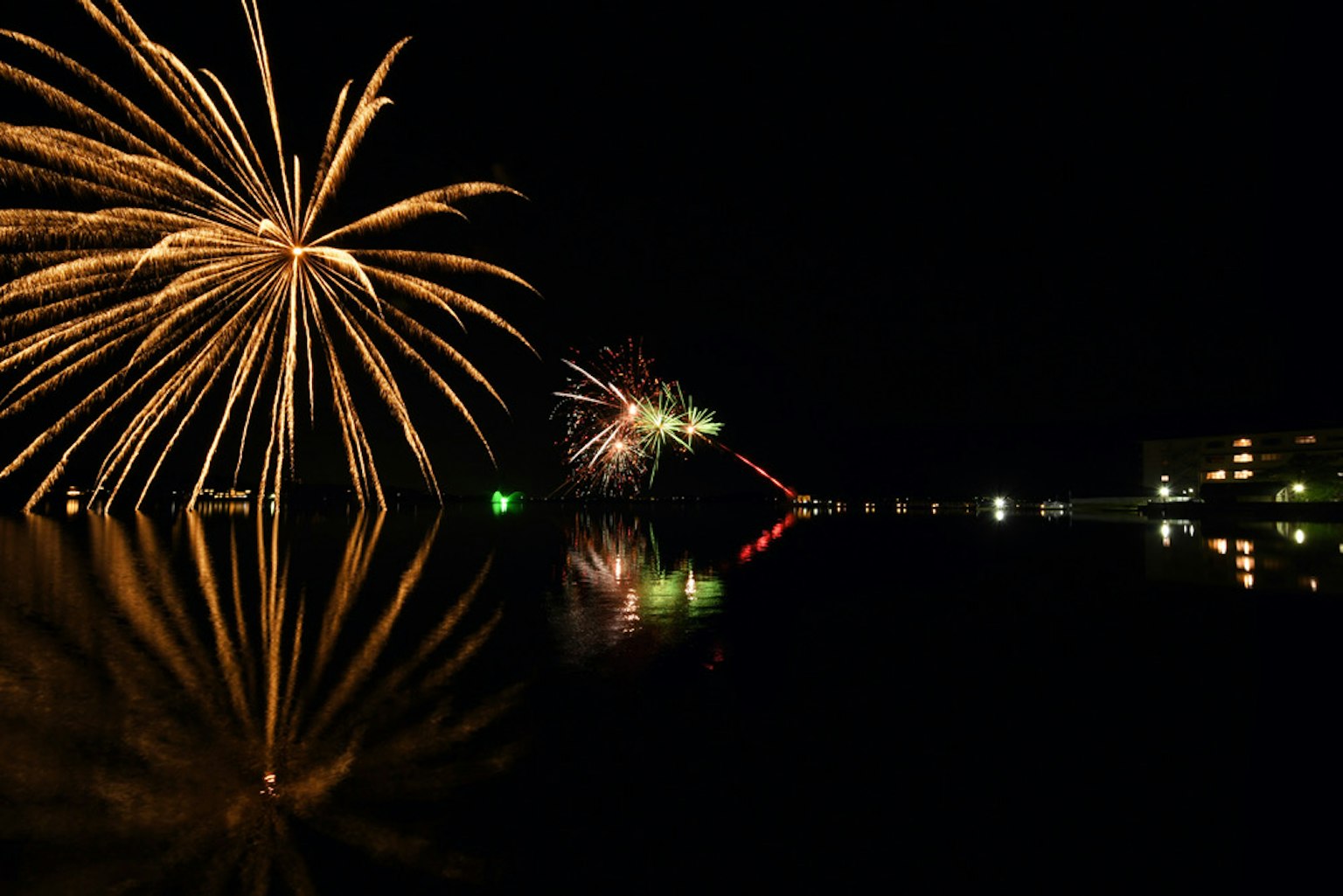 Hermoso espectáculo de fuegos artificiales en el cielo nocturno con reflejos en el agua