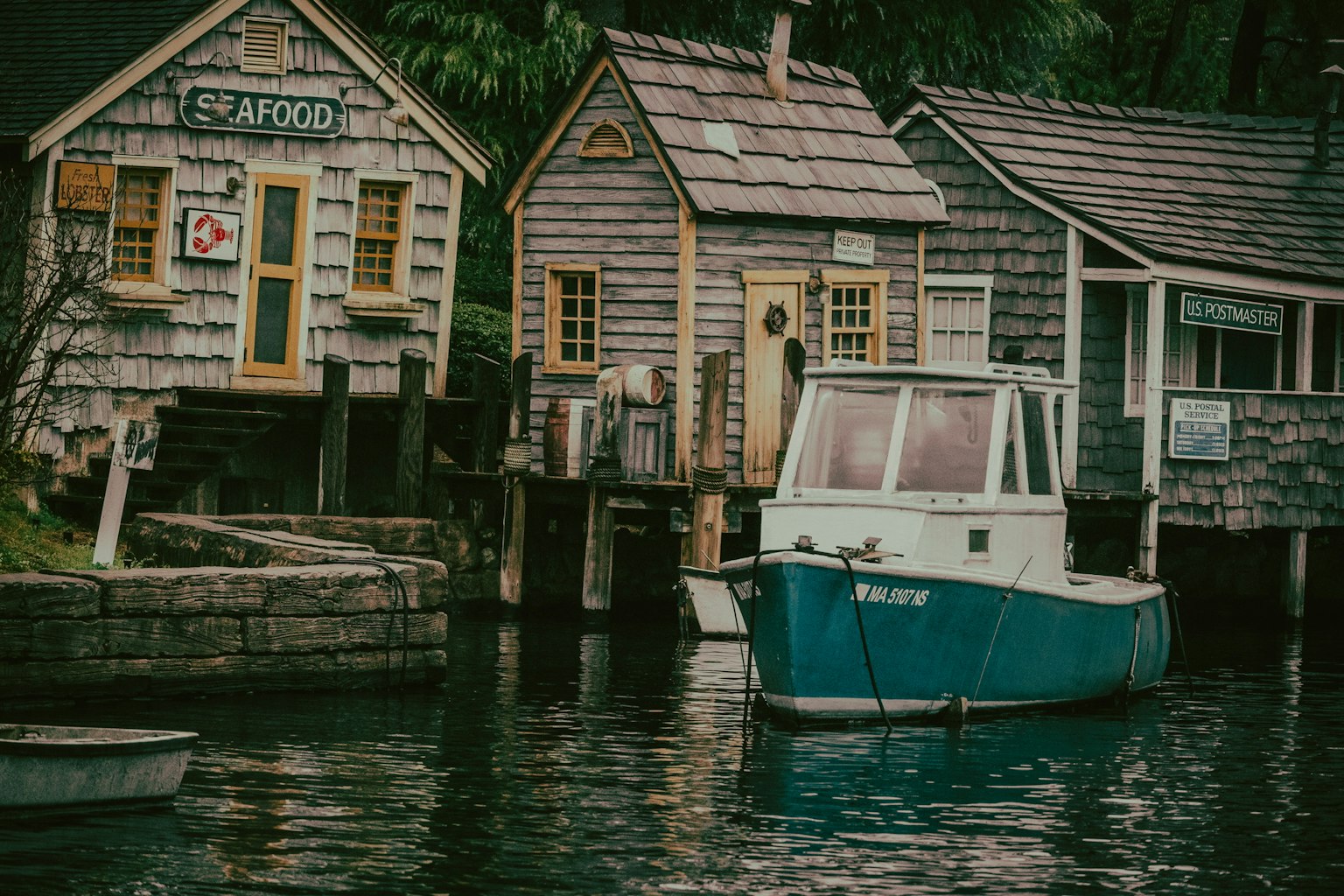Scenic waterfront with a blue boat and rustic wooden buildings