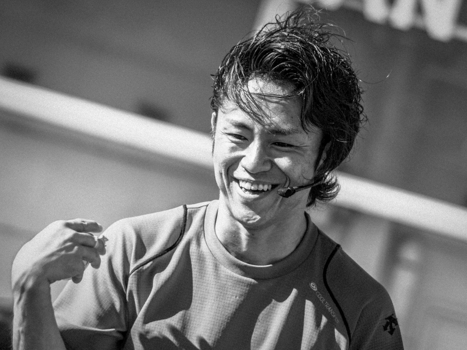 Uomo sorridente con un microfono in un contesto bianco e nero