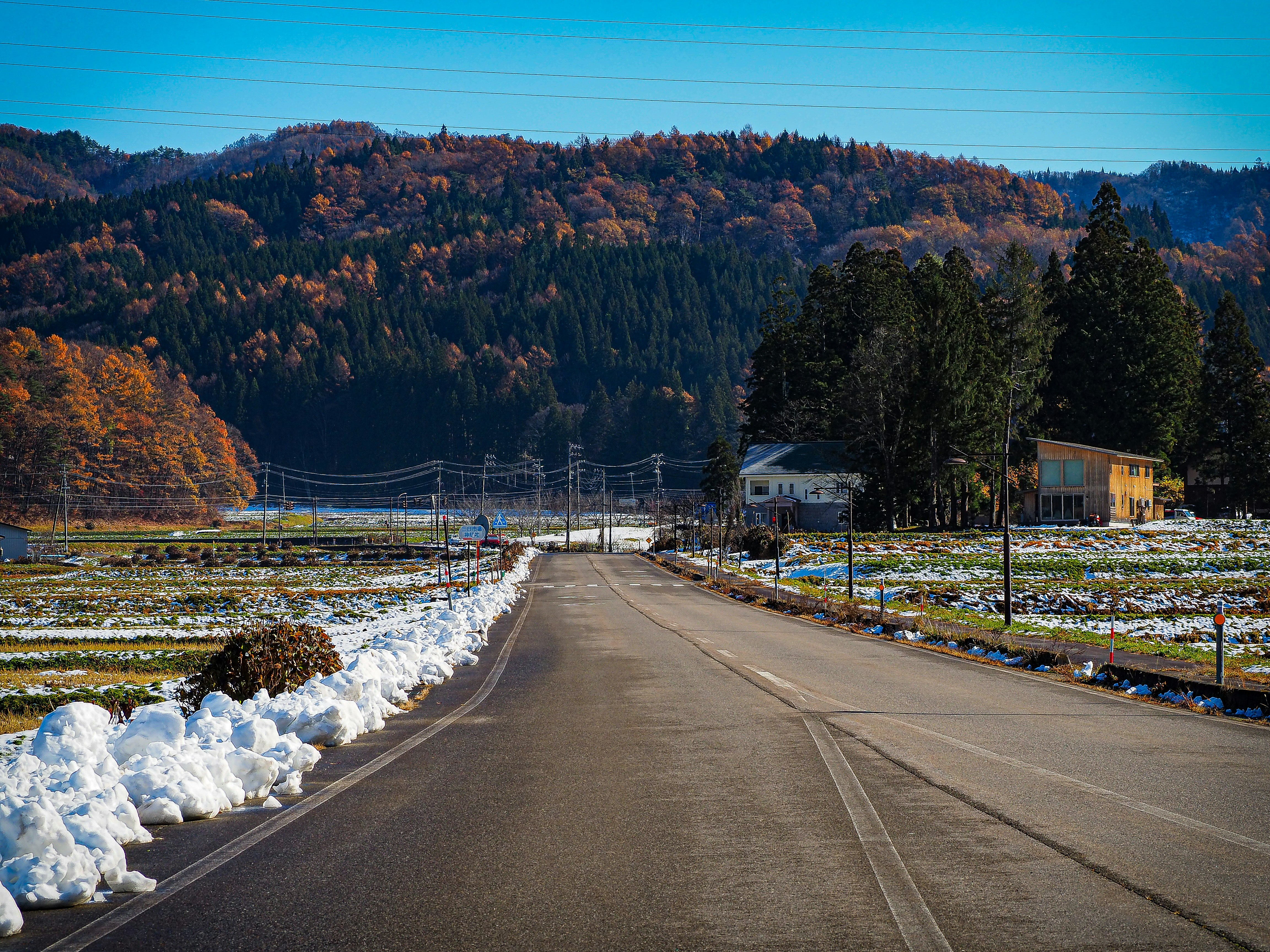 雪の残る田畑と山並みを望む田舎道
