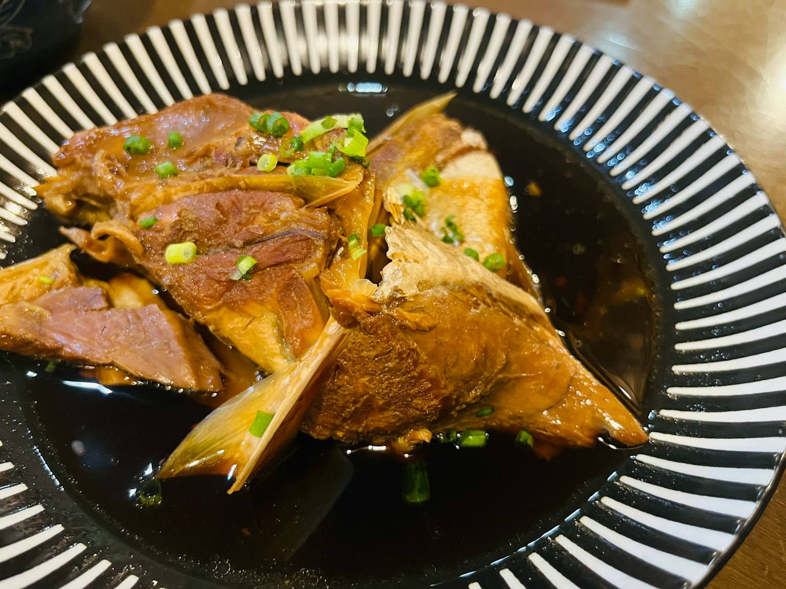 美味的肉菜肴放在黑色盘子上，点缀着青葱