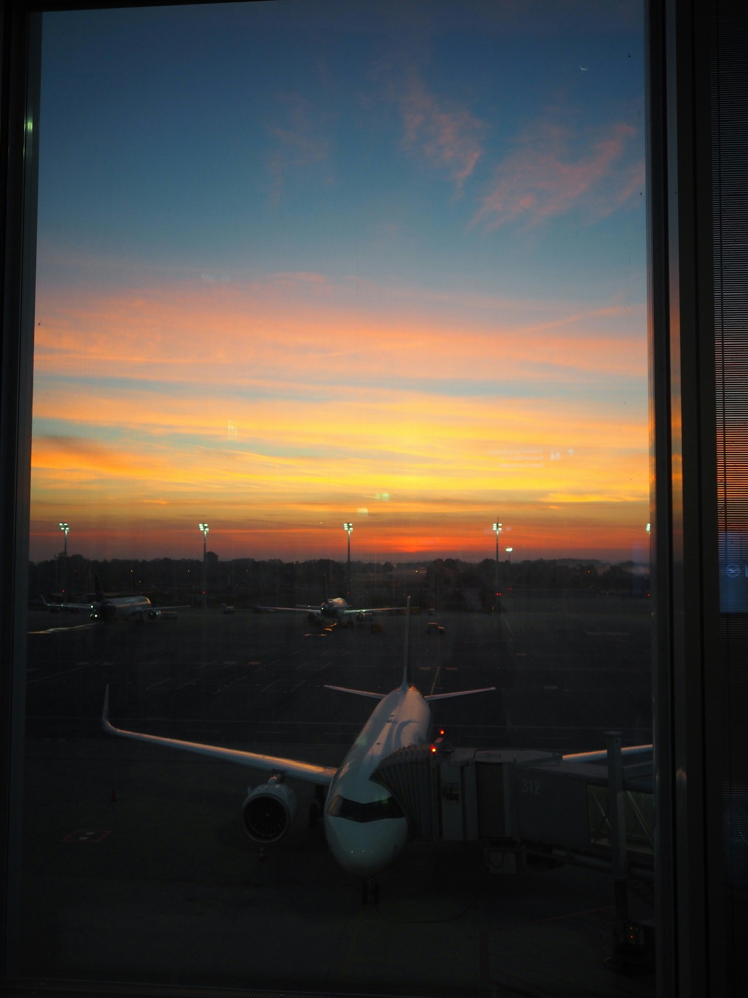 공항 창문에서 바라본 일몰과 주차된 비행기