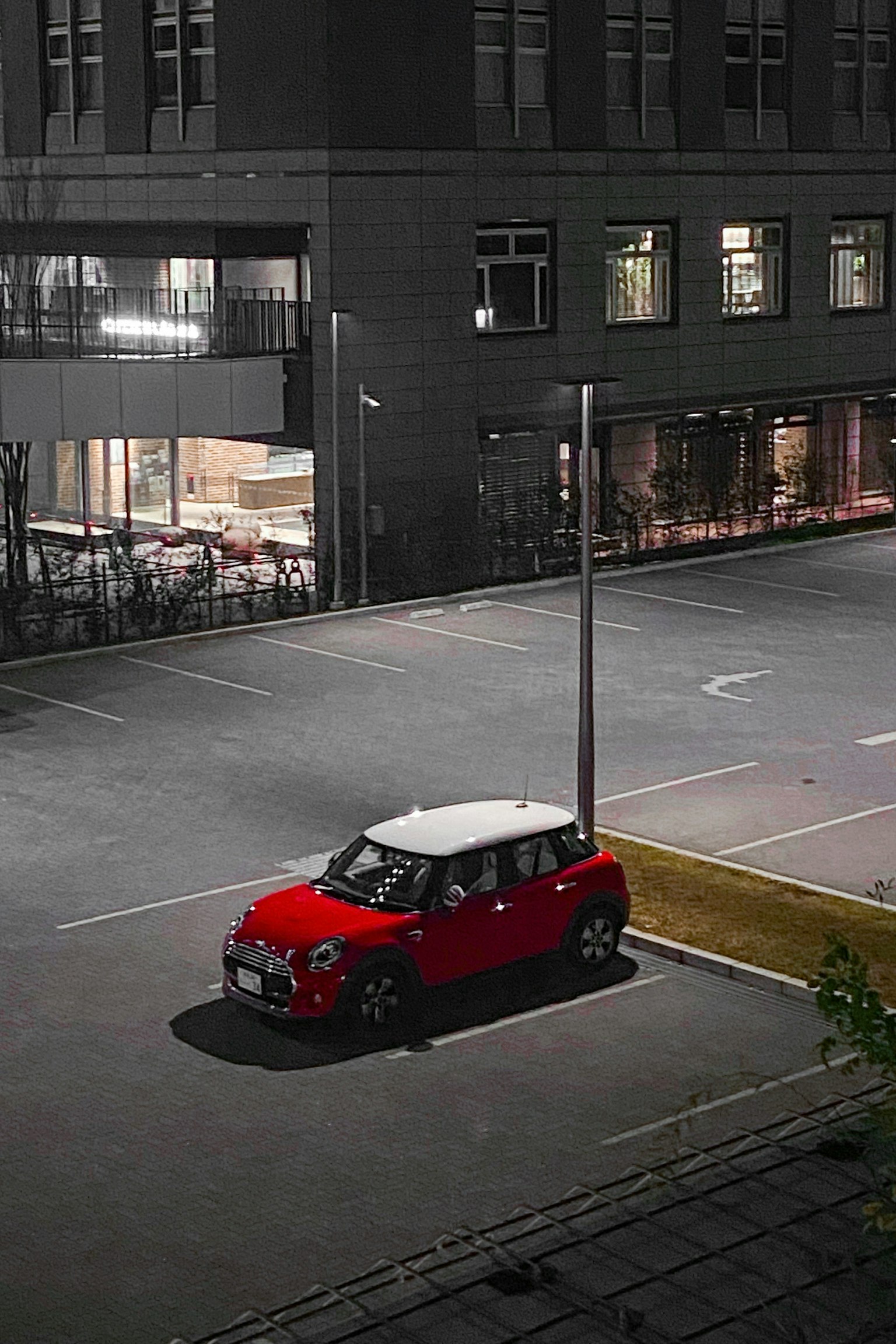 一輛紅色迷你車停在昏暗的停車場