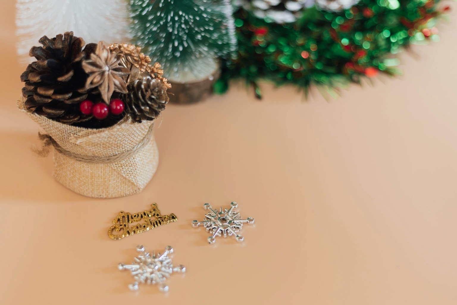 Imagen de decoración navideña con piñas, bayas rojas, copos de nieve plateados y guirnalda verde