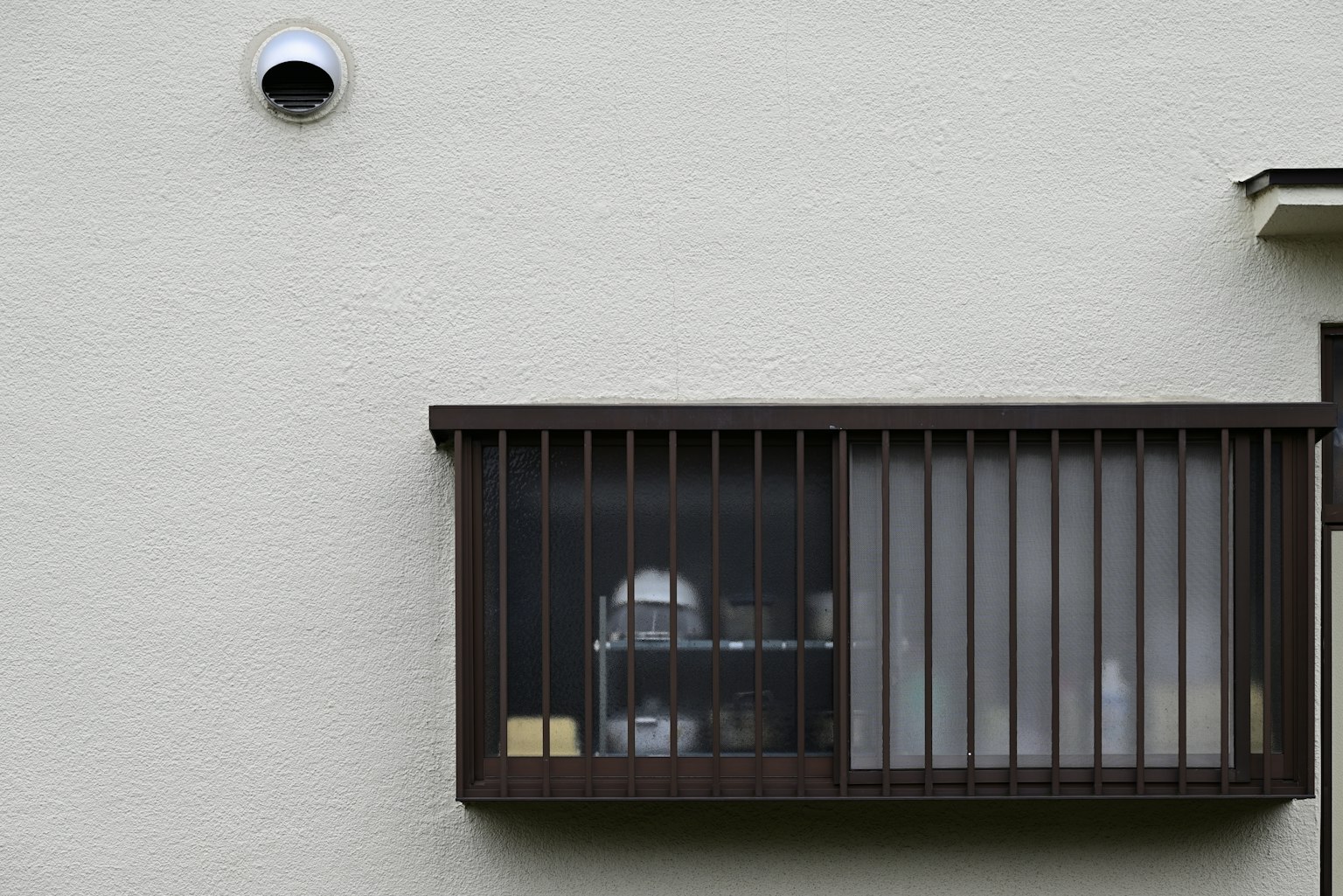 Eine an der Wand montierte Kamera neben einem Holzfenster mit Gittern und Regalen