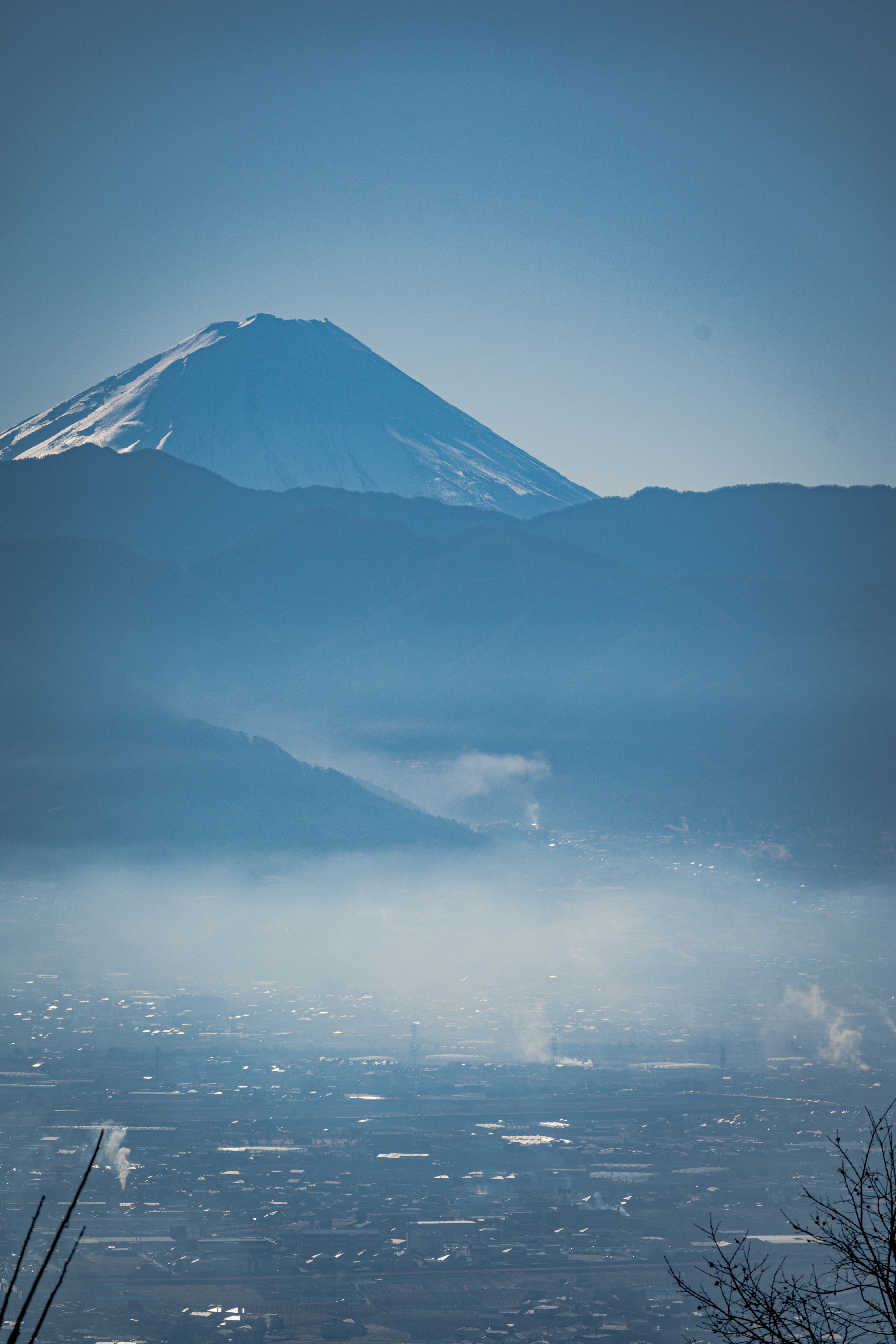 霧のかかった街並みと雪を抱く山の眺望