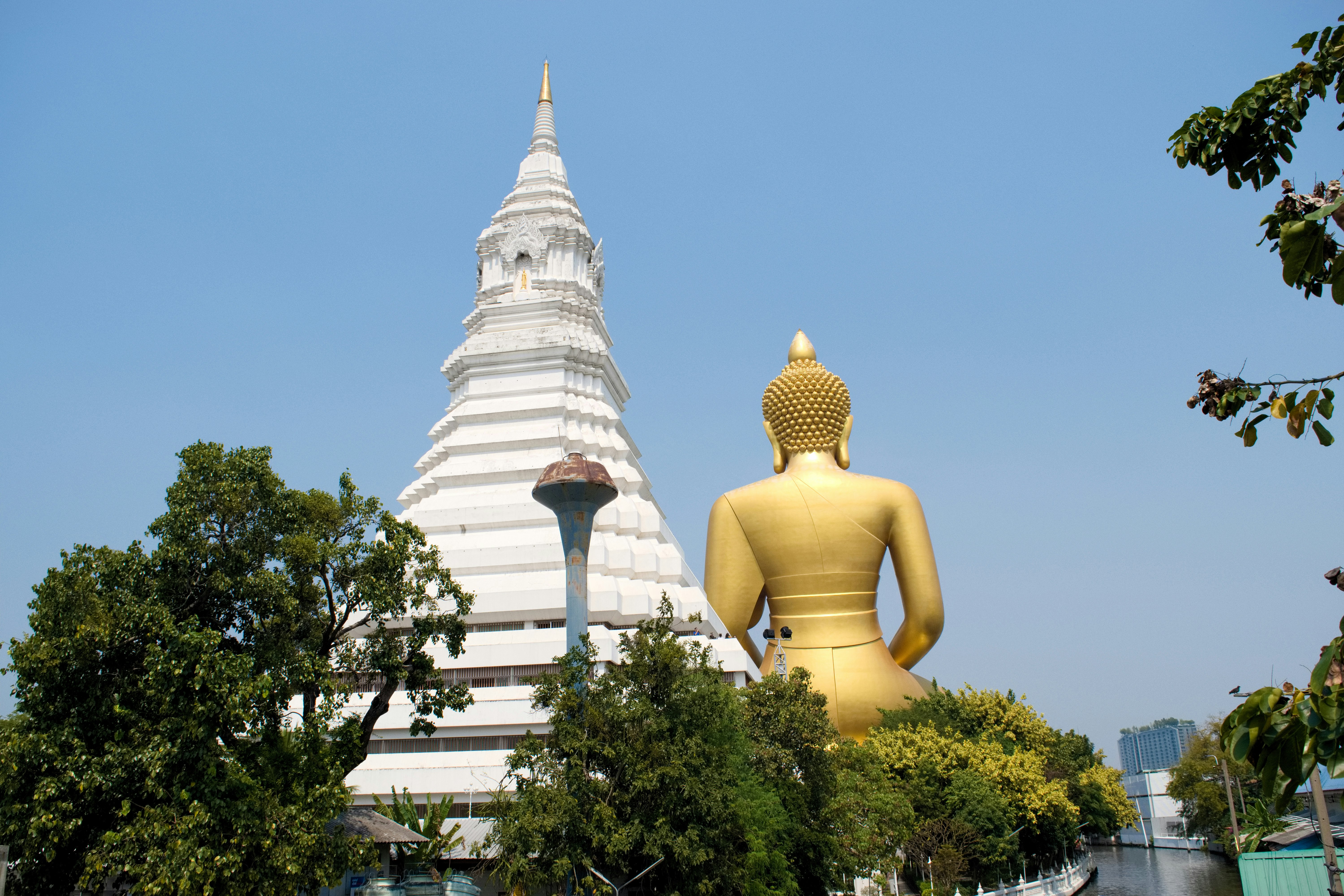 黄金の仏像と白い寺院の塔が並ぶ屋外景観