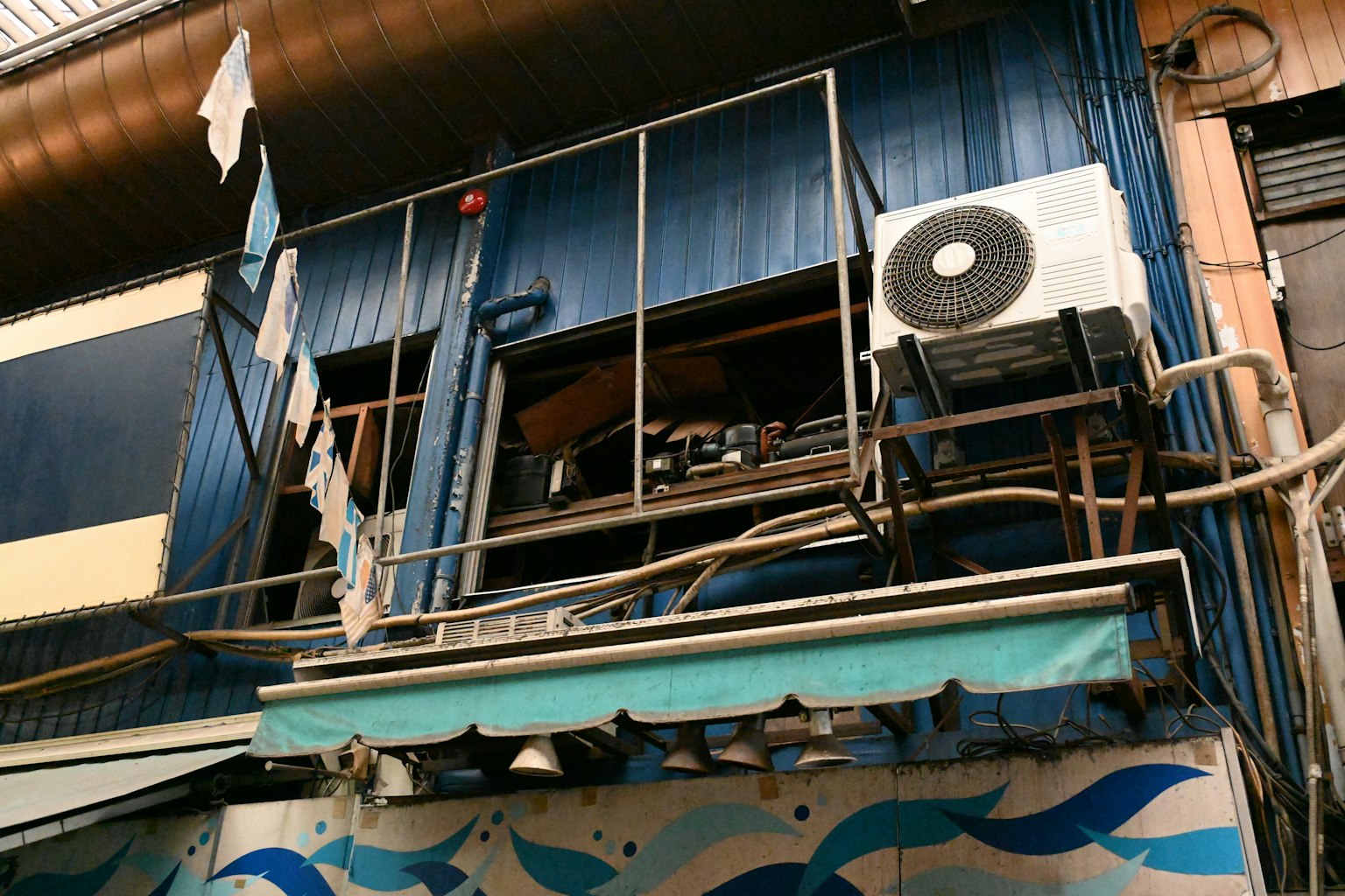Bâtiment avec une façade bleue comportant une unité de climatisation sur le balcon et des vêtements suspendus