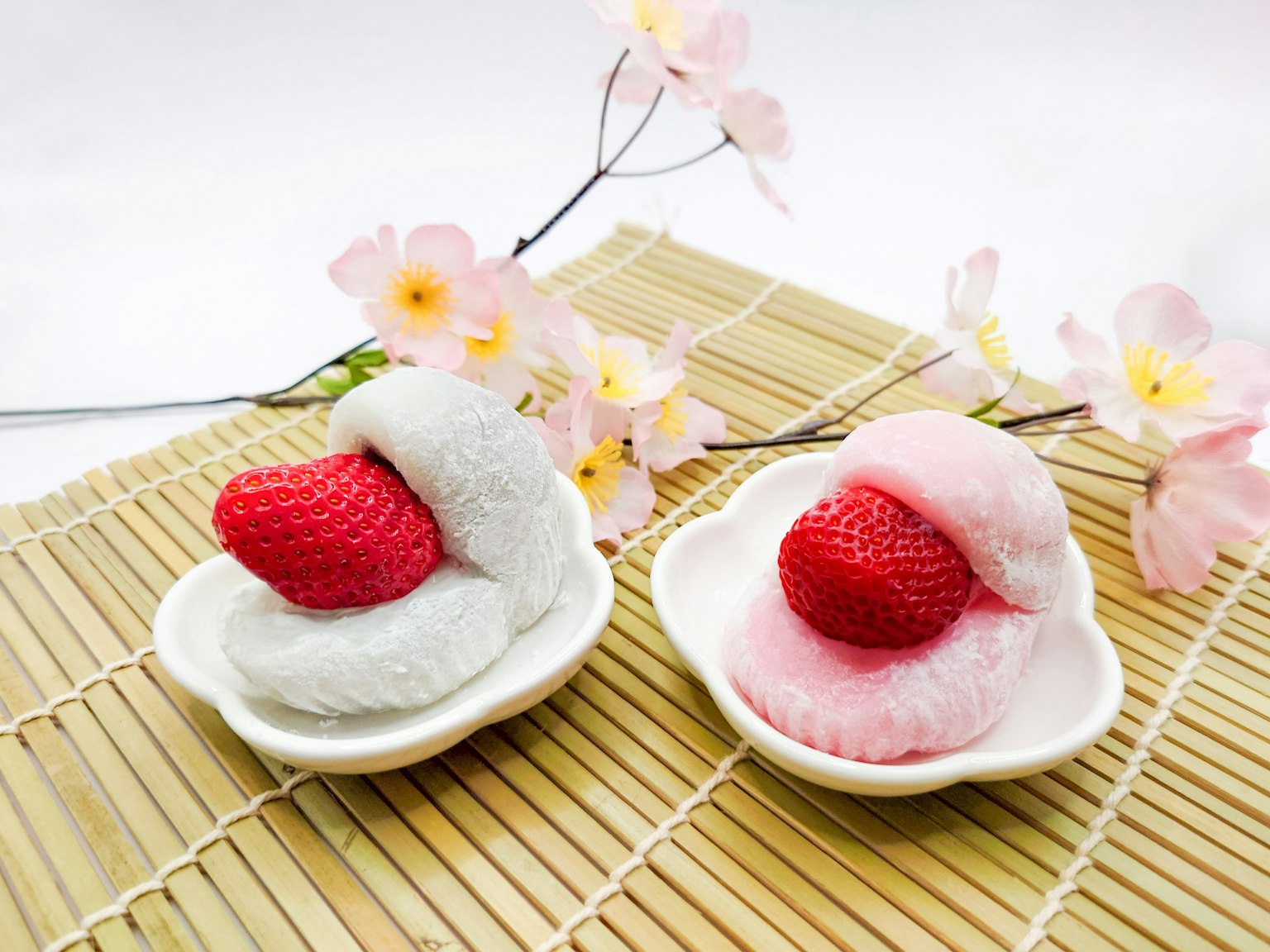 Hai món tráng miệng mochi với dâu tây được bọc bên trong trên đĩa trắng