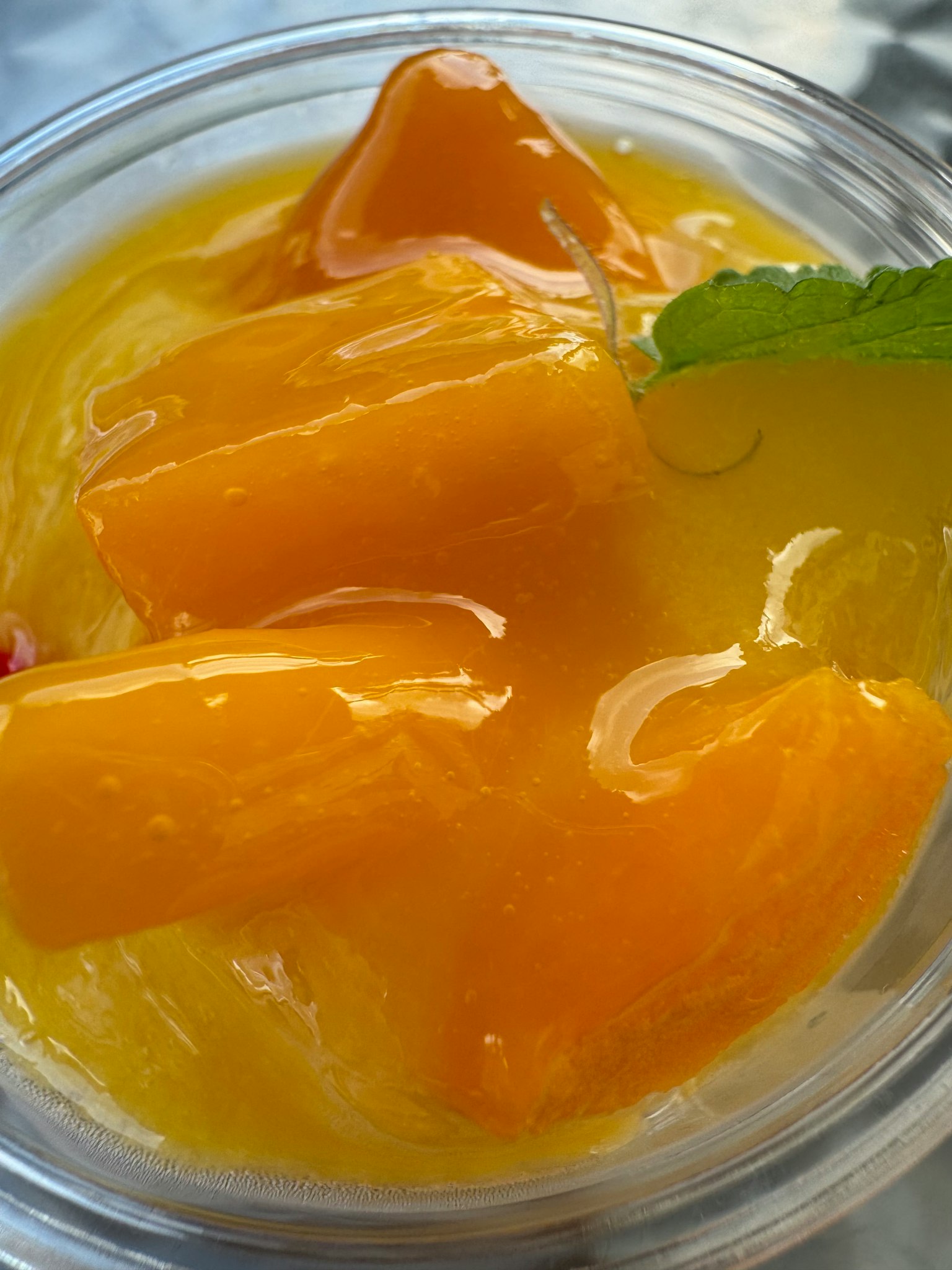 Primo piano di un dessert di mango vibrante con foglie di menta fresca