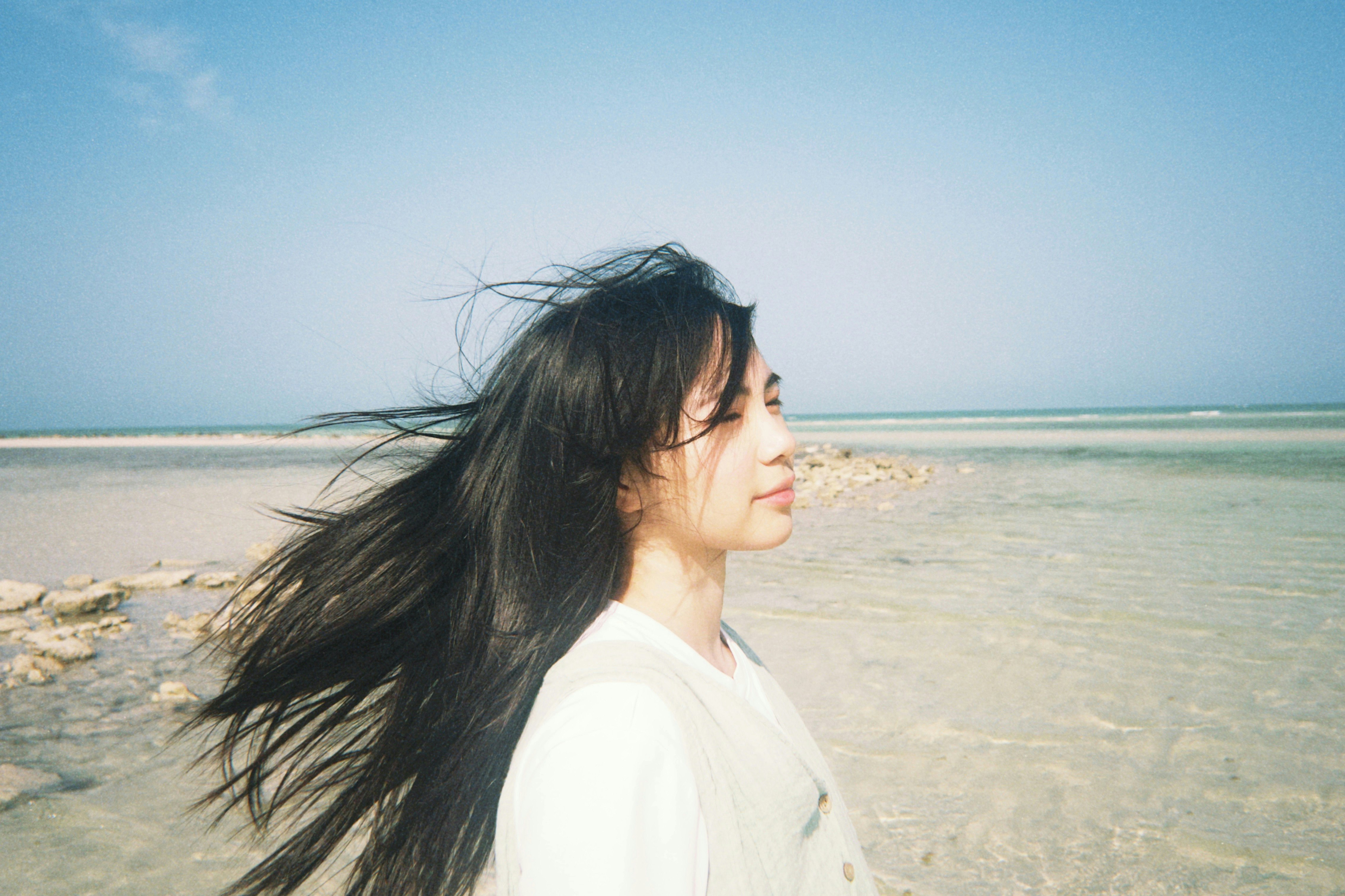 海辺を風に吹かれる女性の横顔