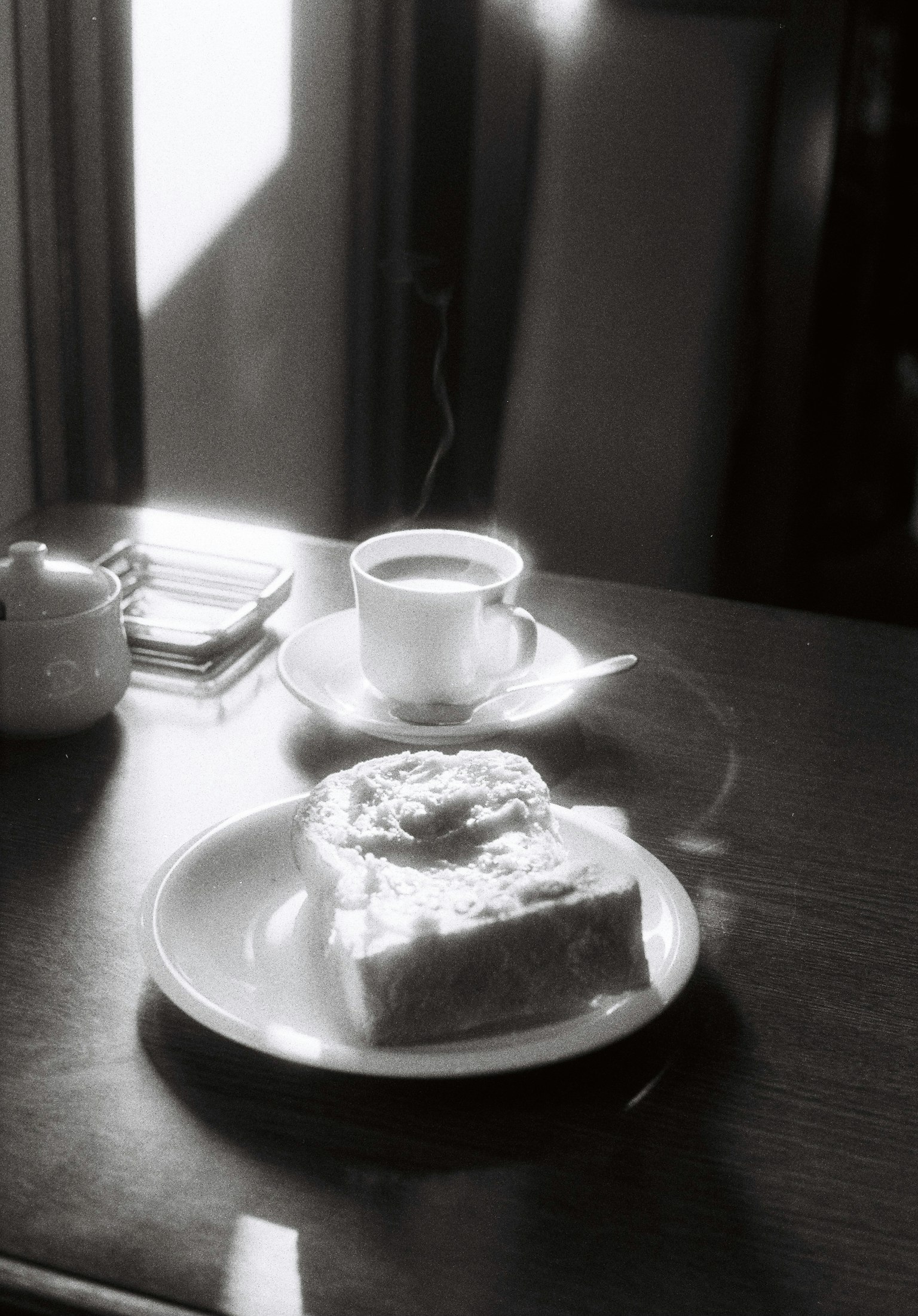 テーブルの上に置かれたコーヒーとケーキのモノクロ写真