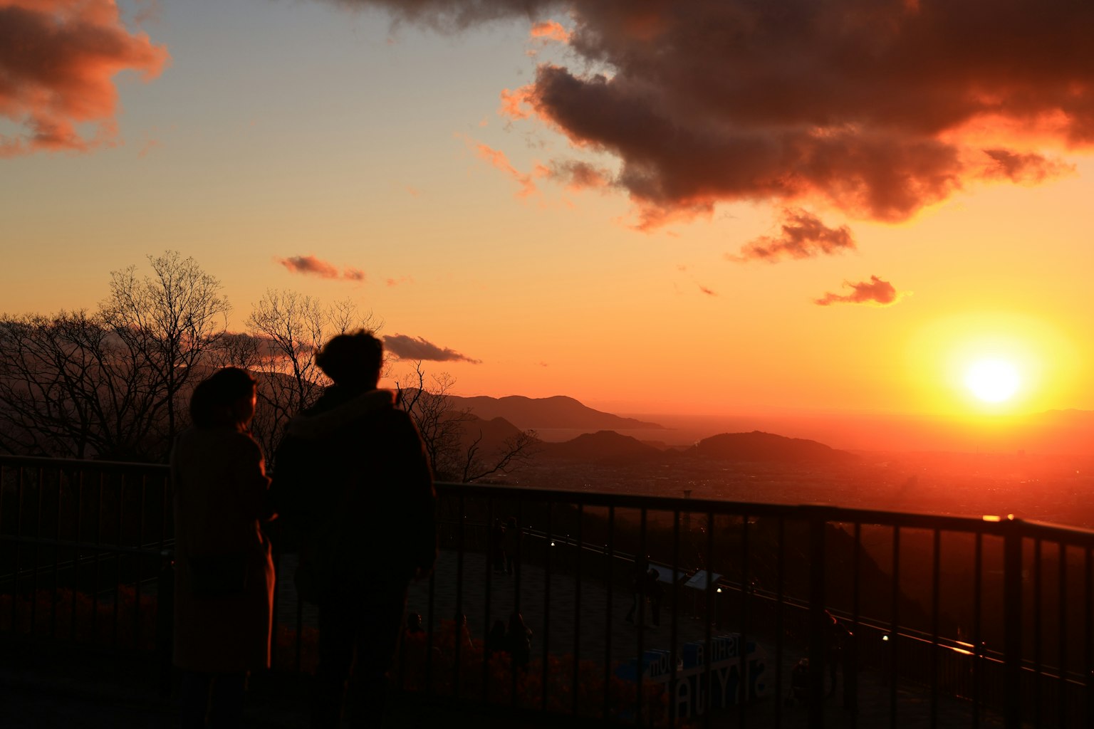 Silhouette di due persone che osservano un tramonto con un cielo colorato