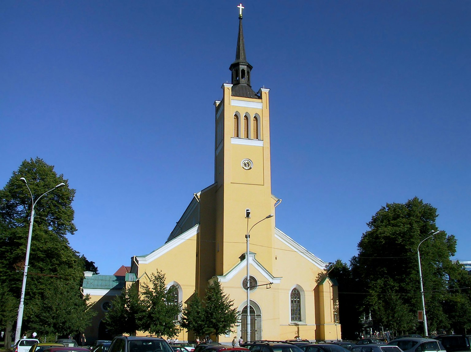 Außenansicht einer gelben Kirche mit hohem Turm