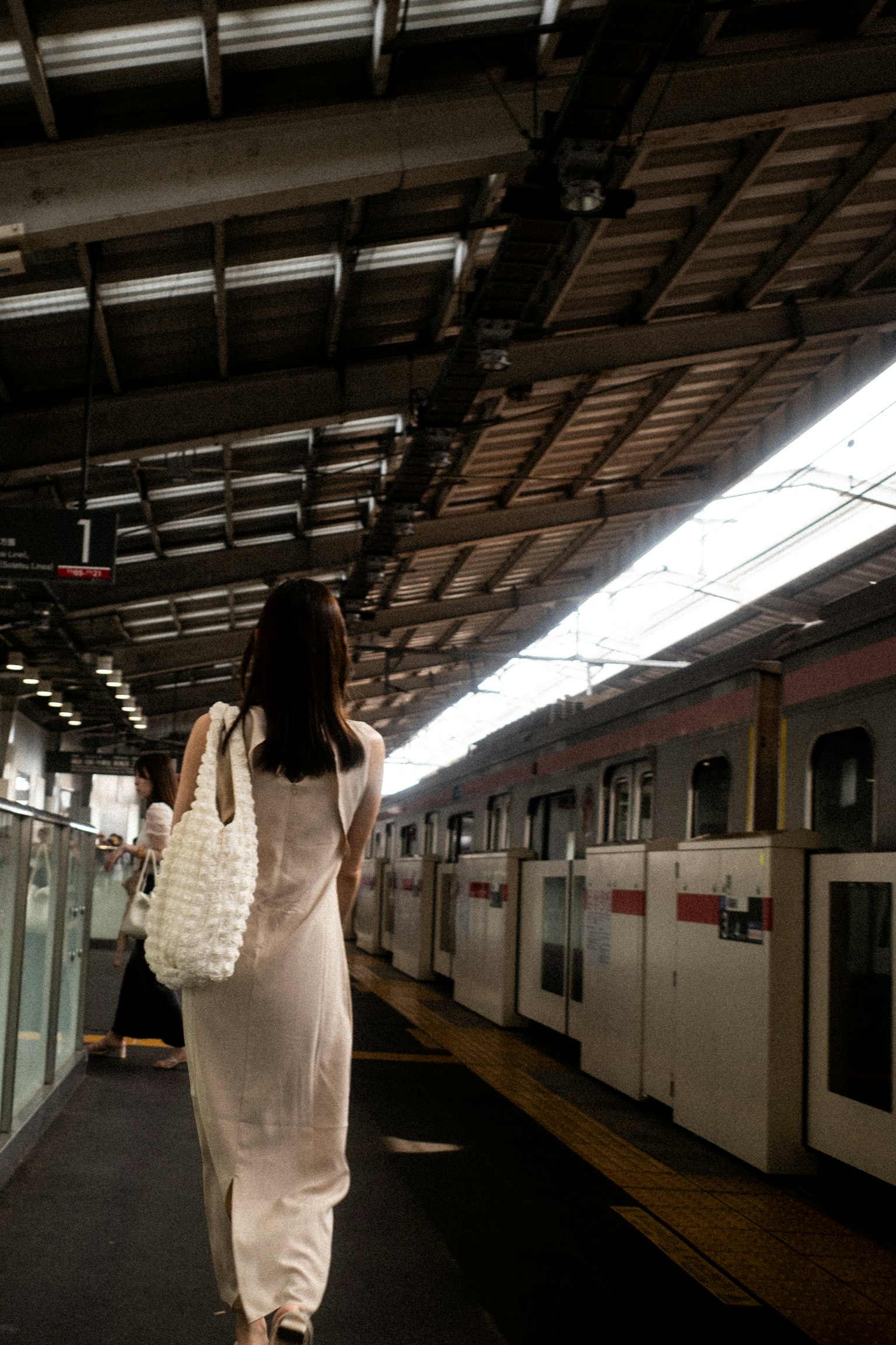 A woman walking towards a train at a station