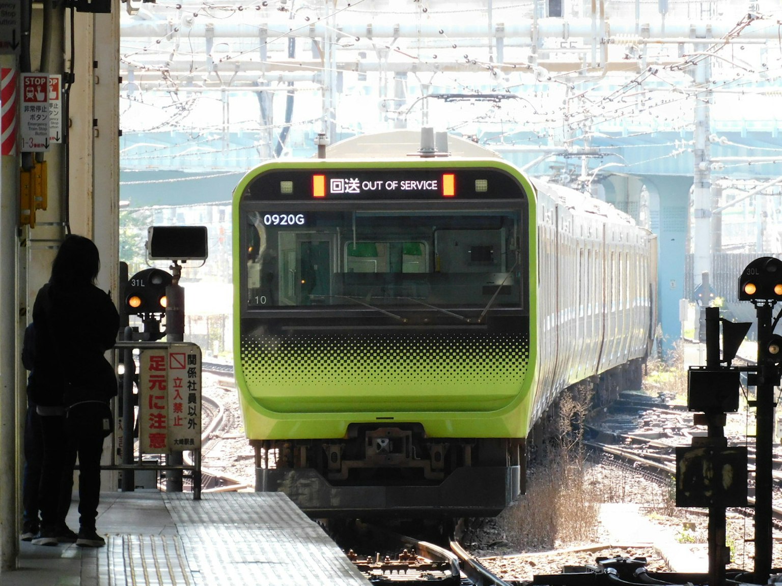 รถไฟสีเขียวมาถึงสถานี ผู้หญิงยืนอยู่บนชานชาลา