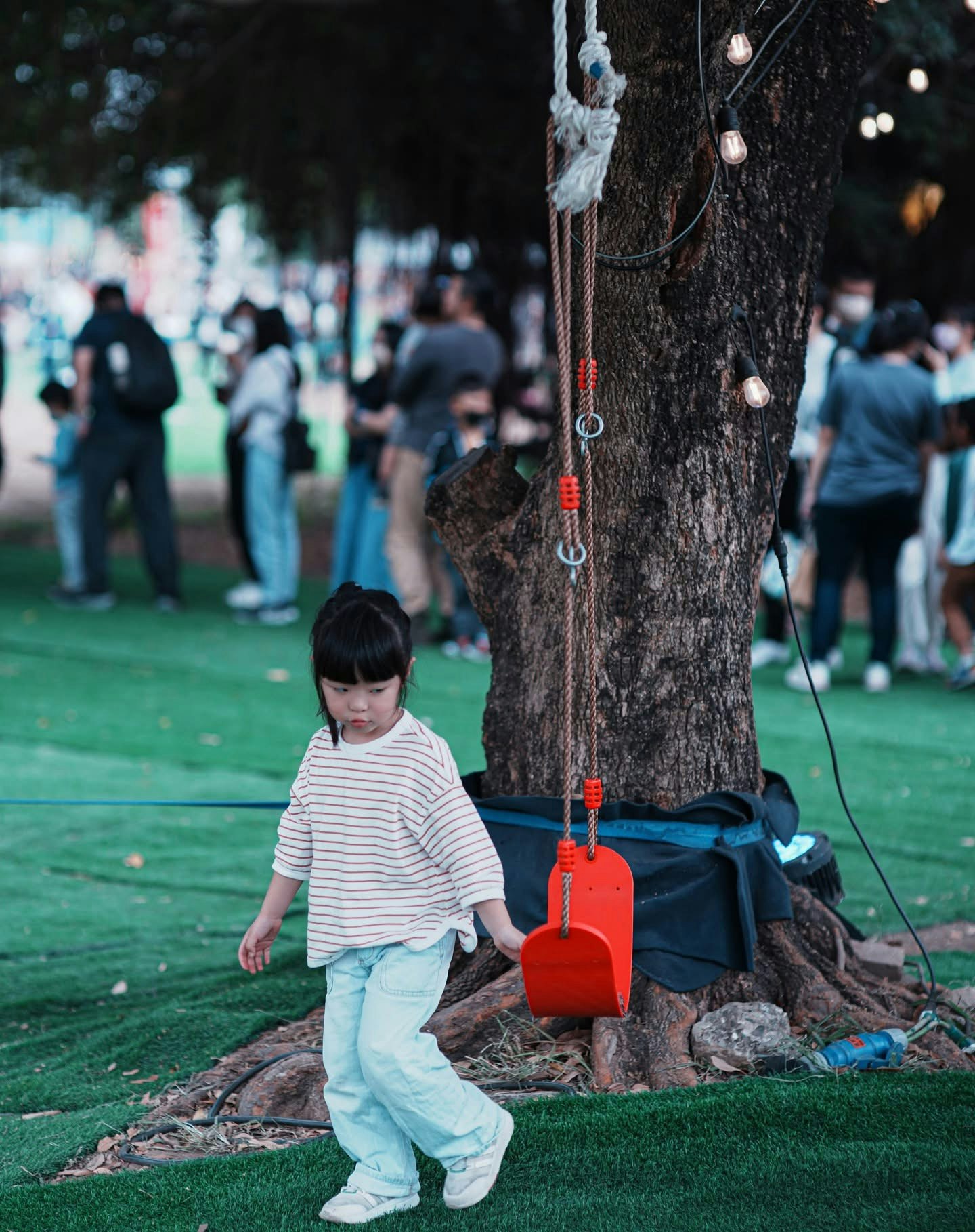 公園の芝生で遊ぶ小さな子どもと木のそばの道具