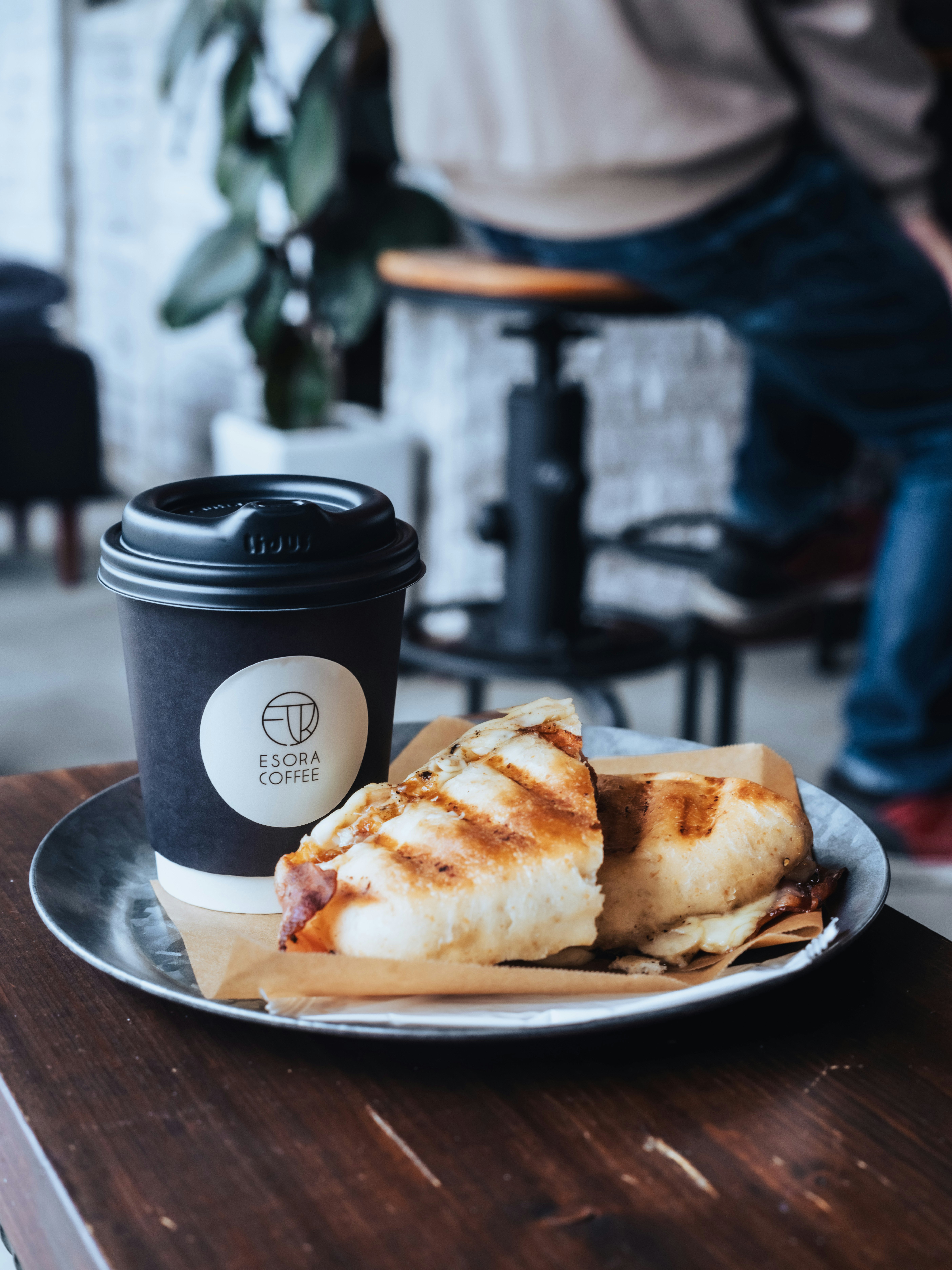 ESORA COFFEEの紙コップとパニーニのあるカフェテーブル