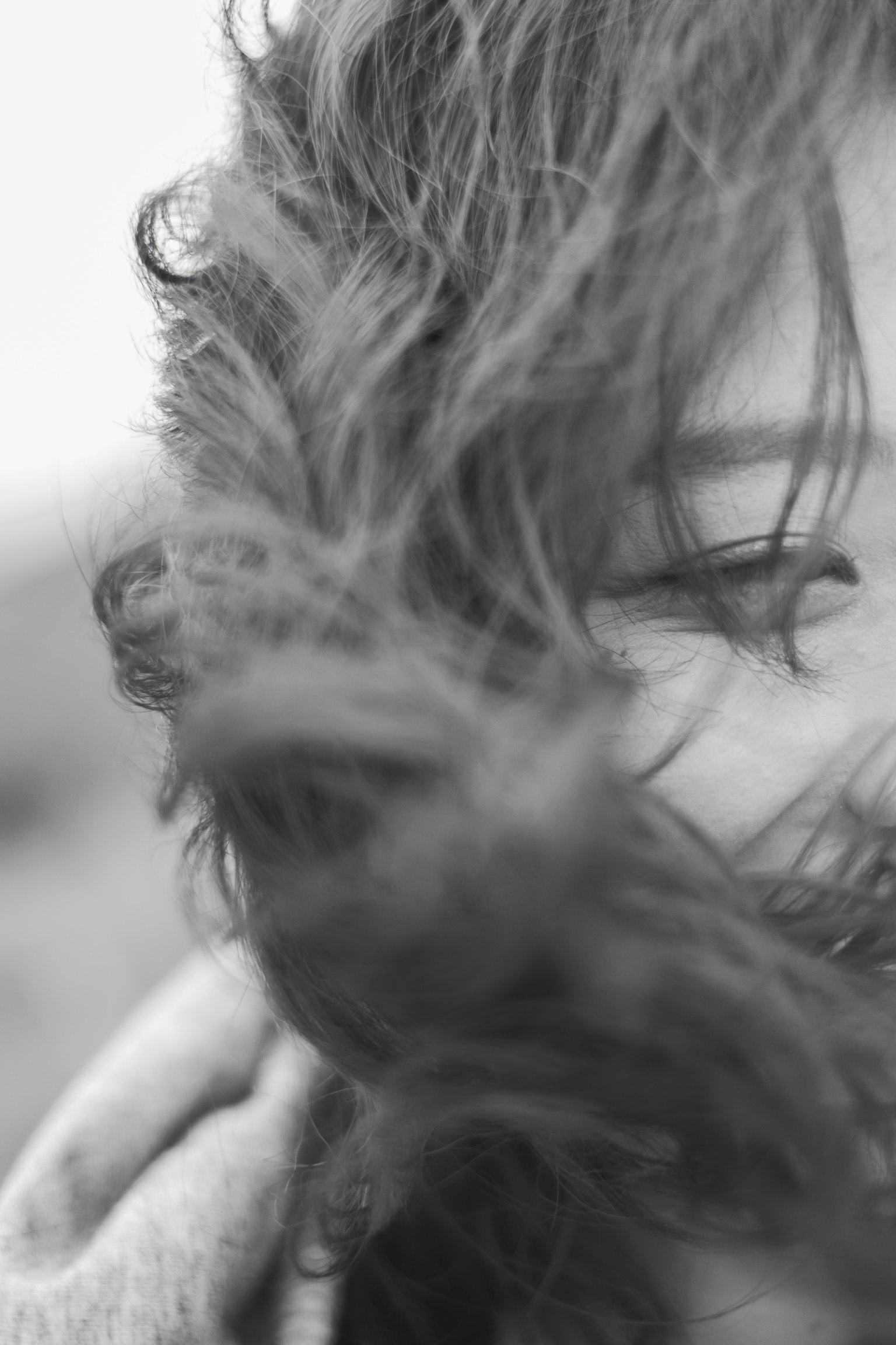 Black and white photo showing part of a woman's face with long hair blowing in the wind
