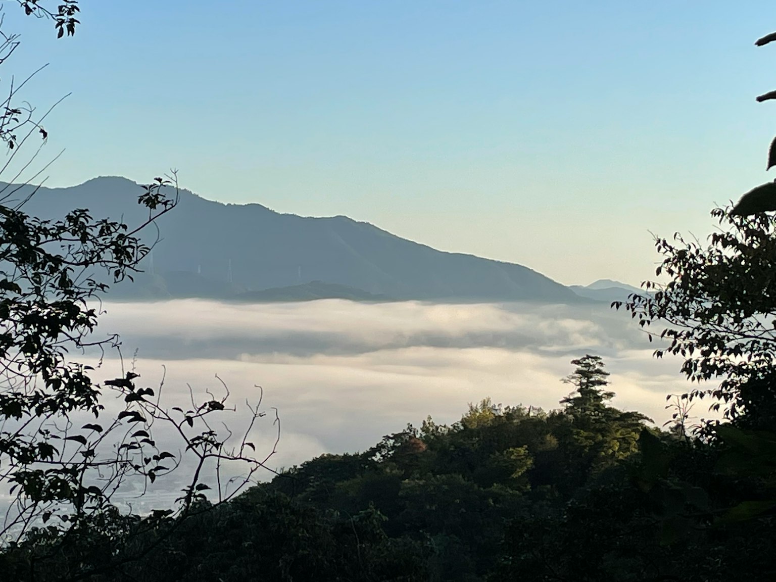 Vista panoramica di montagne coperte di nebbia con cielo blu chiaro