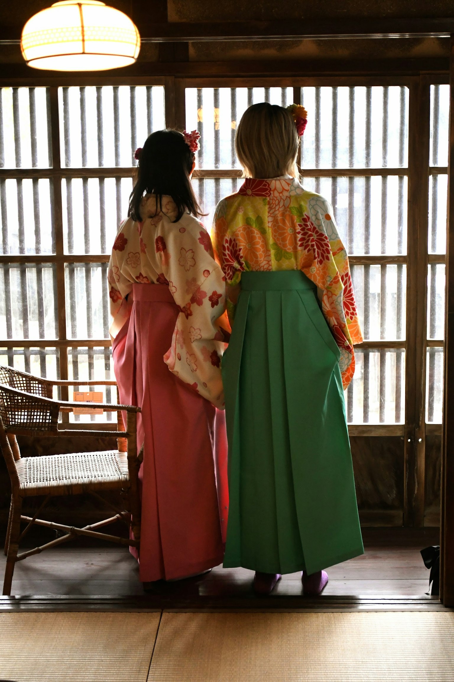 Dua wanita dalam kimono tradisional melihat ke luar jendela