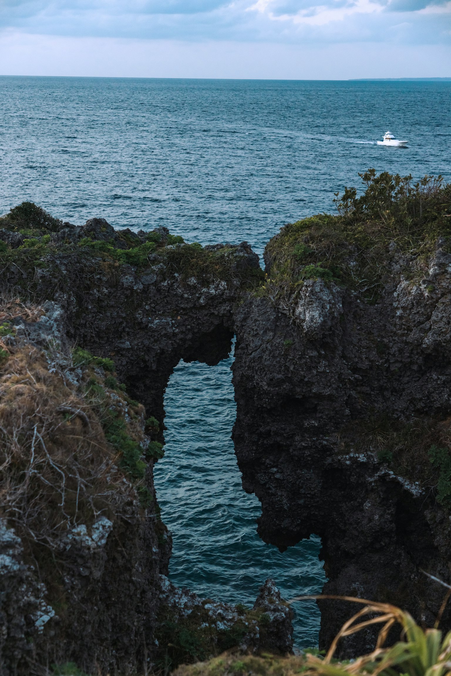 Vista escénica de rocas y mar con un pequeño bote a lo lejos