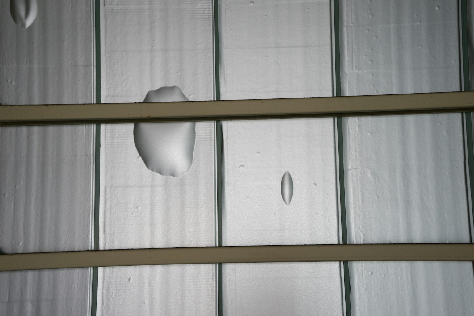 Metal roof with water droplets and dents visible