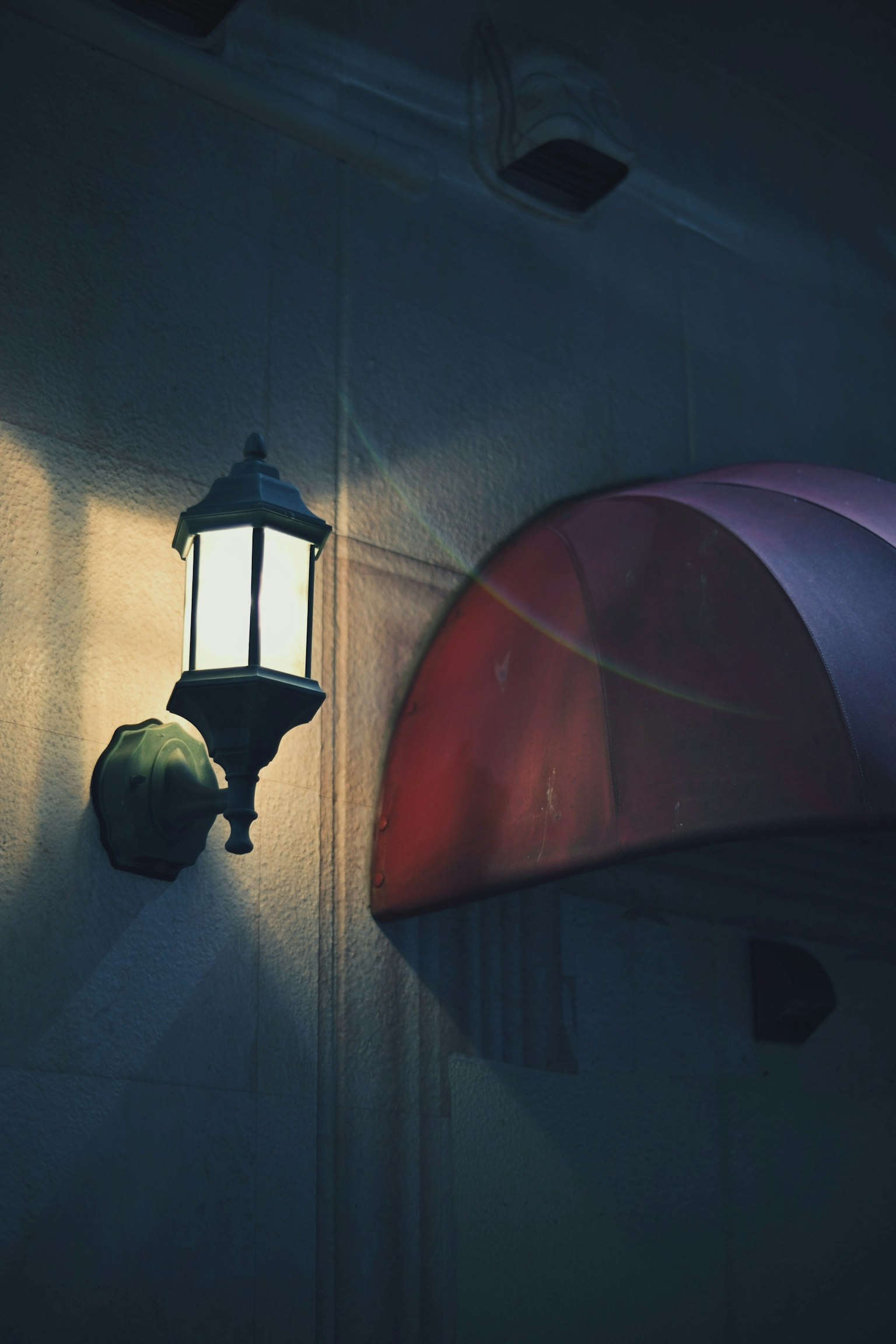 Mur avec un lampadaire et un auvent rouge la nuit