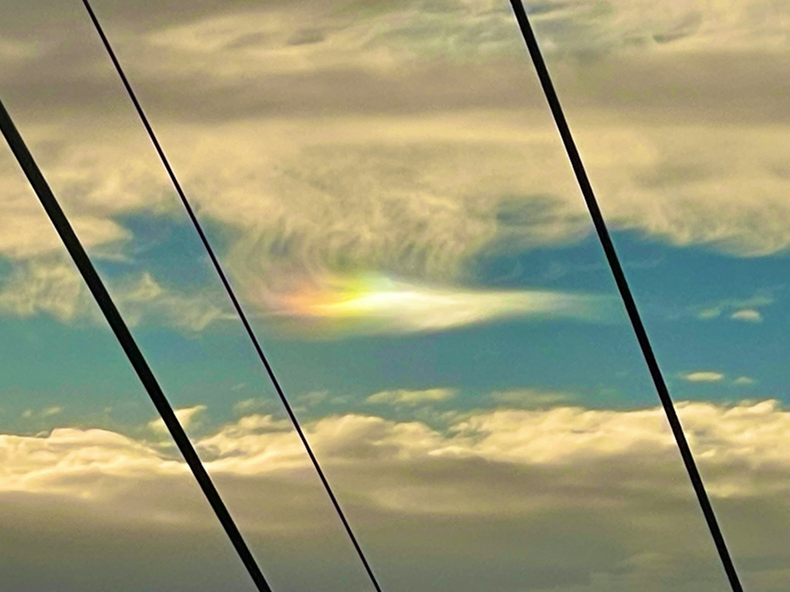 Awan berwarna pelangi di langit dengan garis listrik siluet