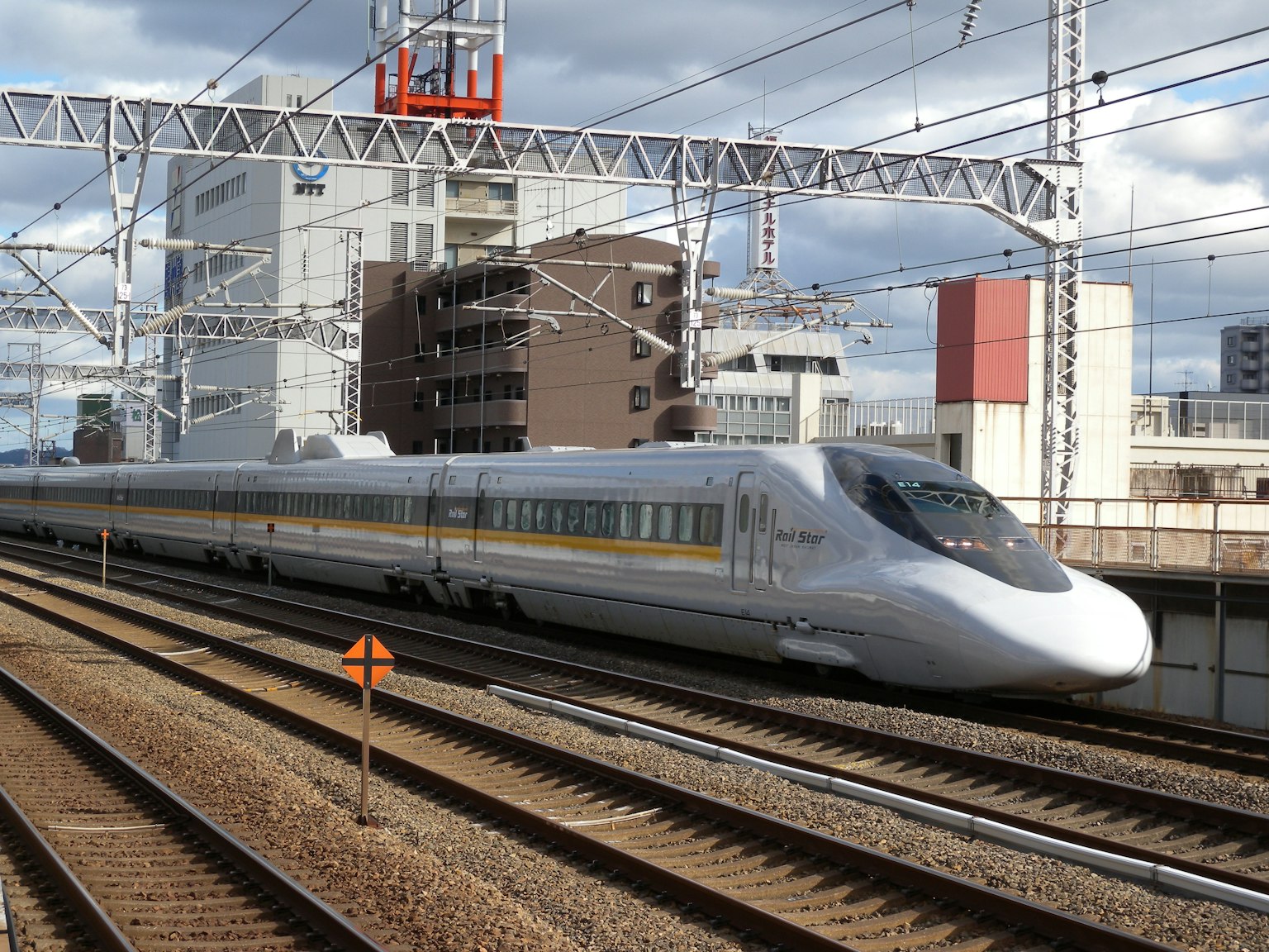 Train Shinkansen roulant le long des rails avec des bâtiments modernes en arrière-plan