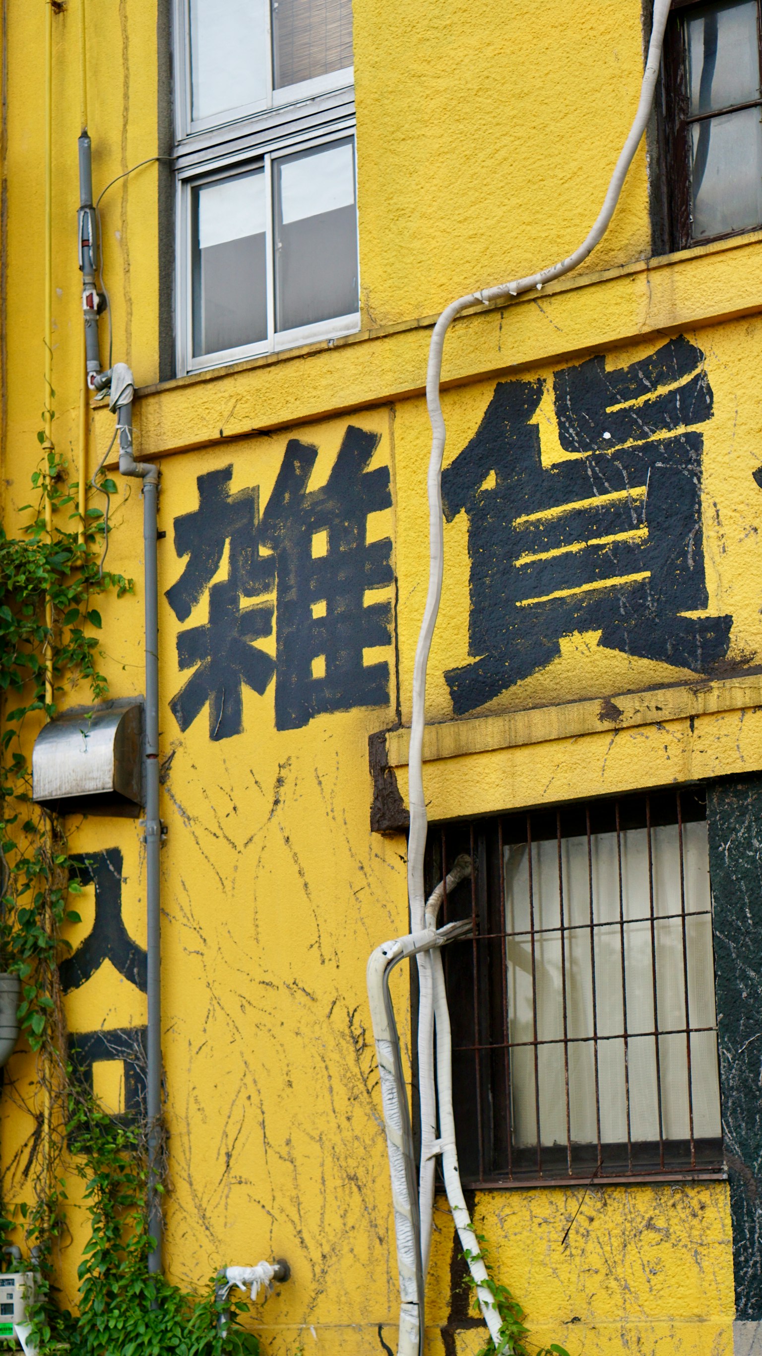 一面黄色的墙上有大黑字写着'杂货'的建筑
