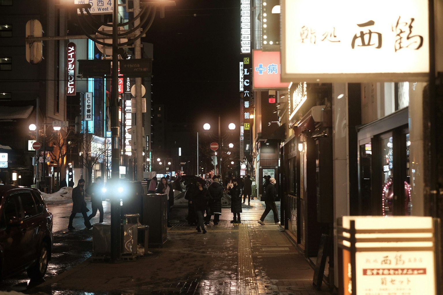Escena de calle nocturna llena de gente Carteles y tiendas iluminadas