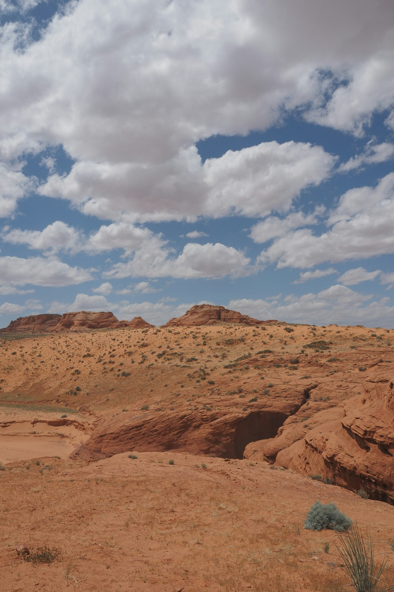 Paysage désertique rouge avec des nuages blancs dans un ciel bleu