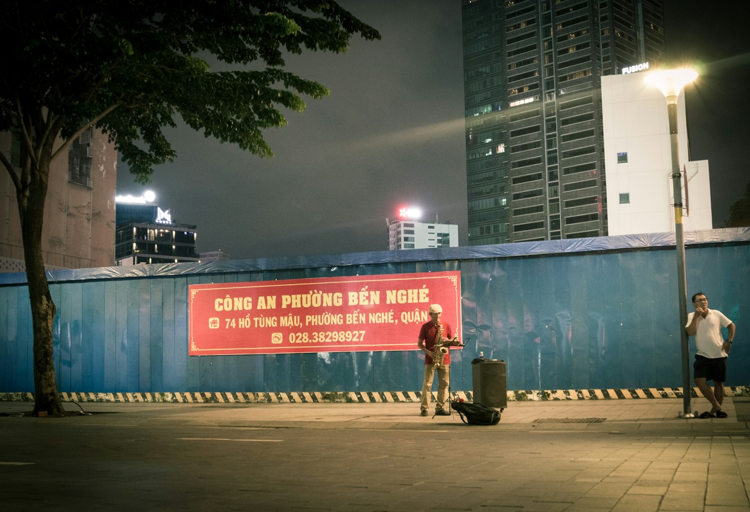 Scena urbana notturna con una persona e un grande striscione rosso