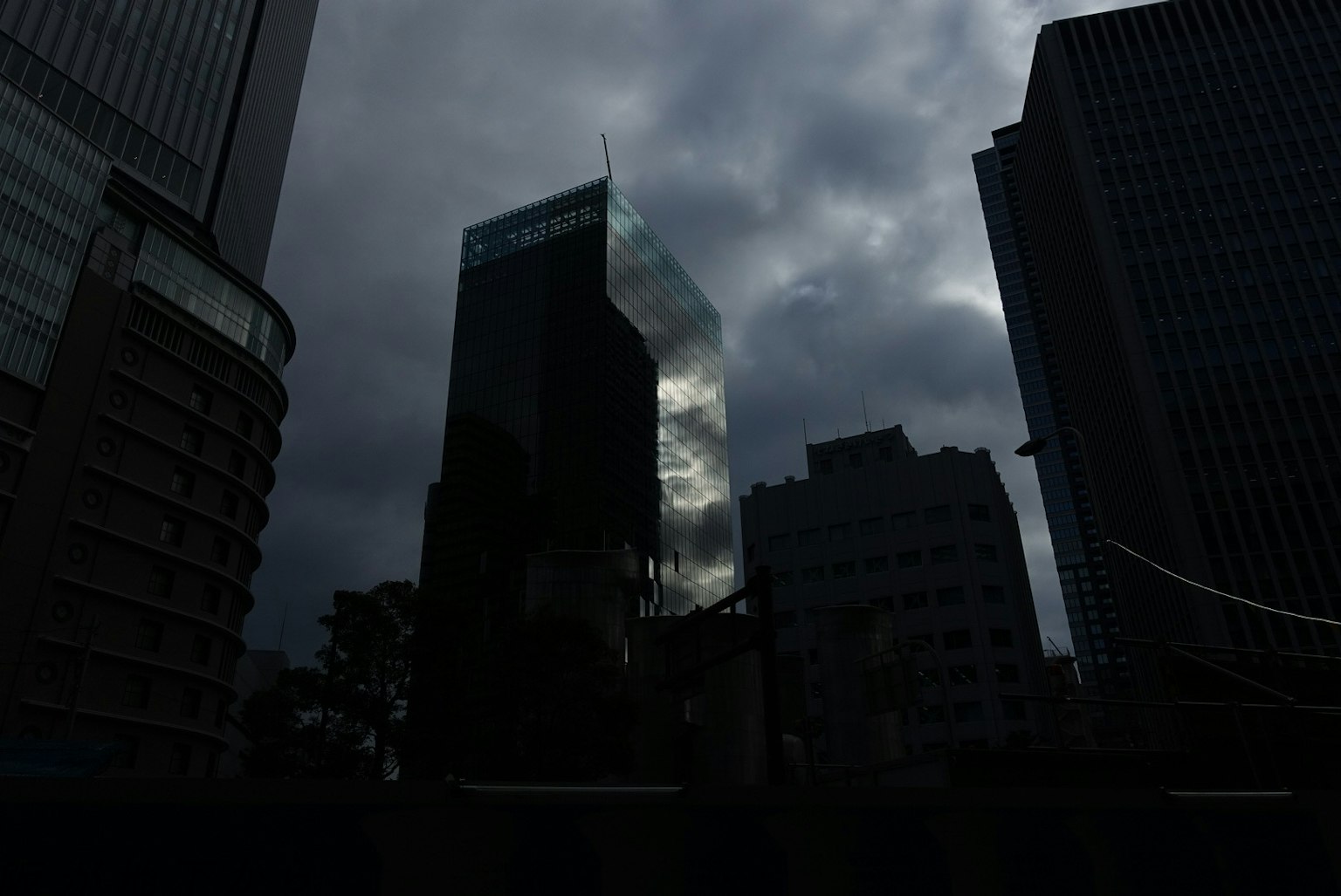 Siluet gedung kota melawan langit mendung gelap dengan kaca reflektif