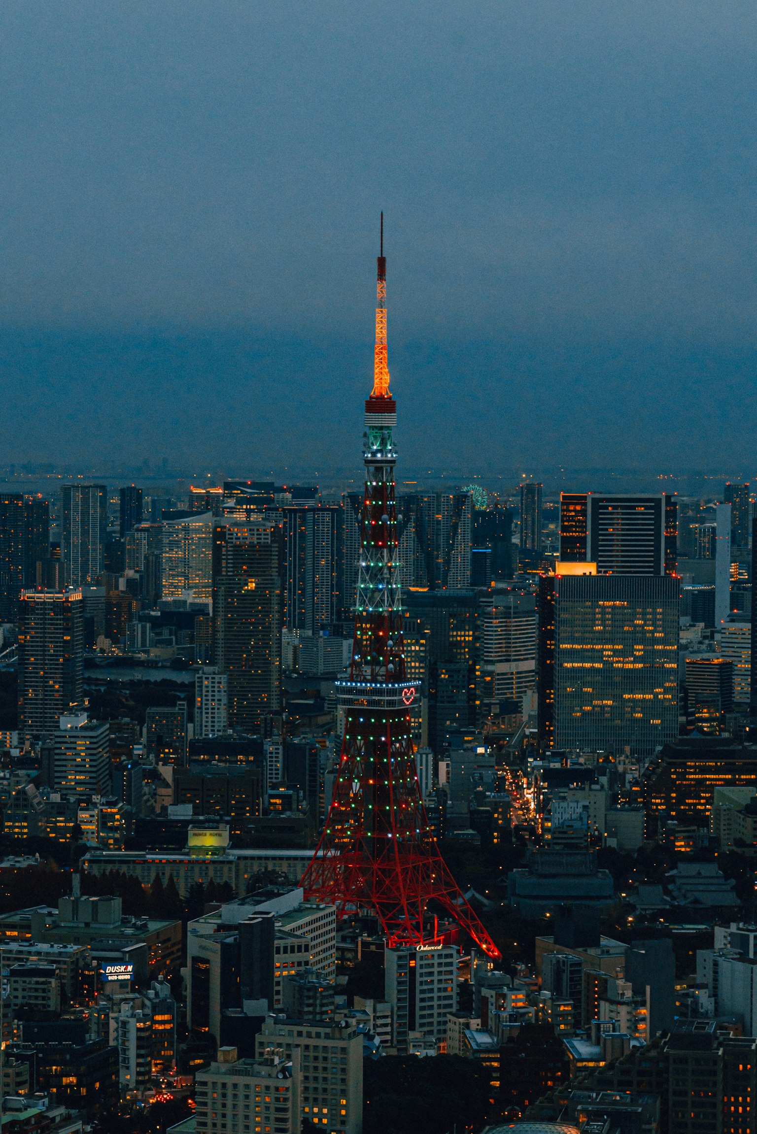 Torre de Tokio iluminada contra el horizonte urbano al anochecer