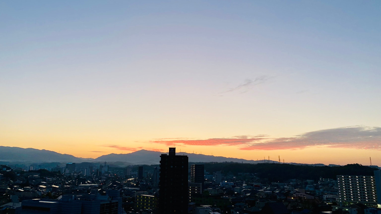 ทิวทัศน์ที่สวยงามของเส้นขอบฟ้าในยามพระอาทิตย์ตกดินพร้อมวิวเมืองและภูเขา