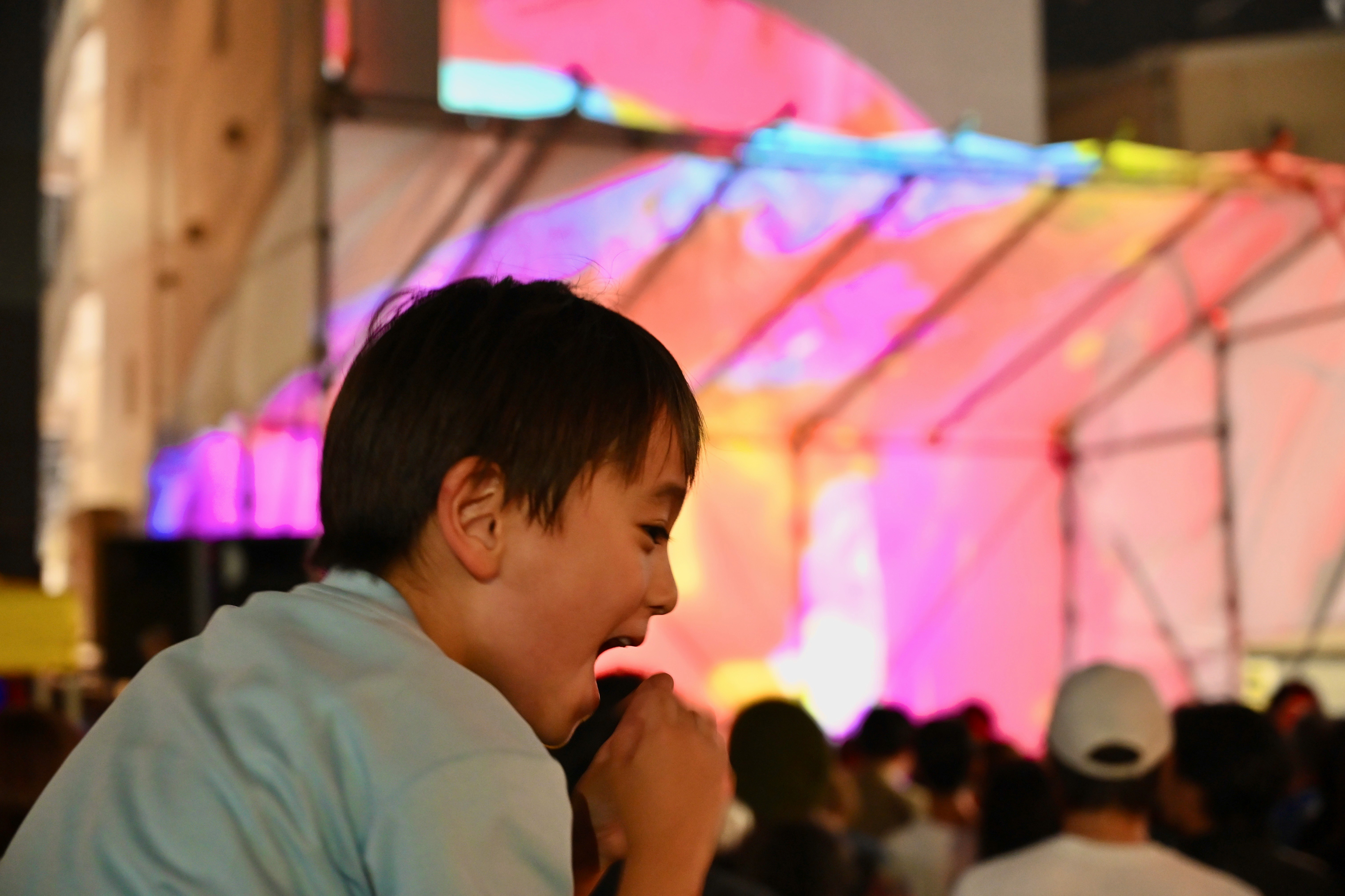 屋内のイベント会場でマイクを持つ子ども