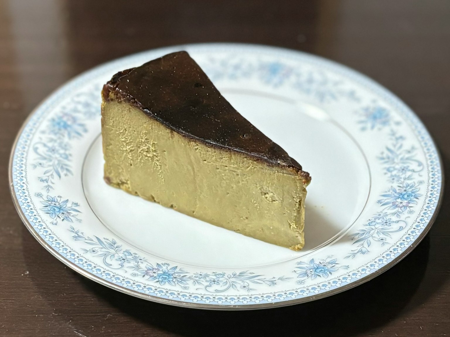 Una fetta di cheesecake cremosa su un piatto floreale blu