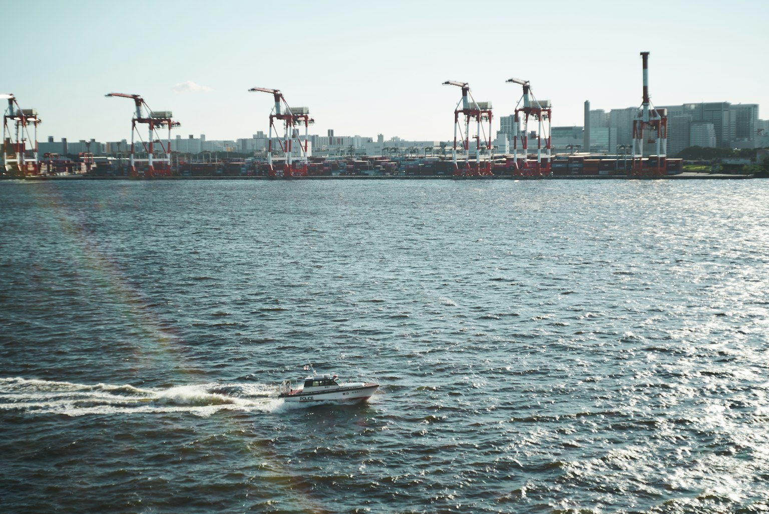 Vue de grues dans un port avec un petit bateau naviguant sur l'eau